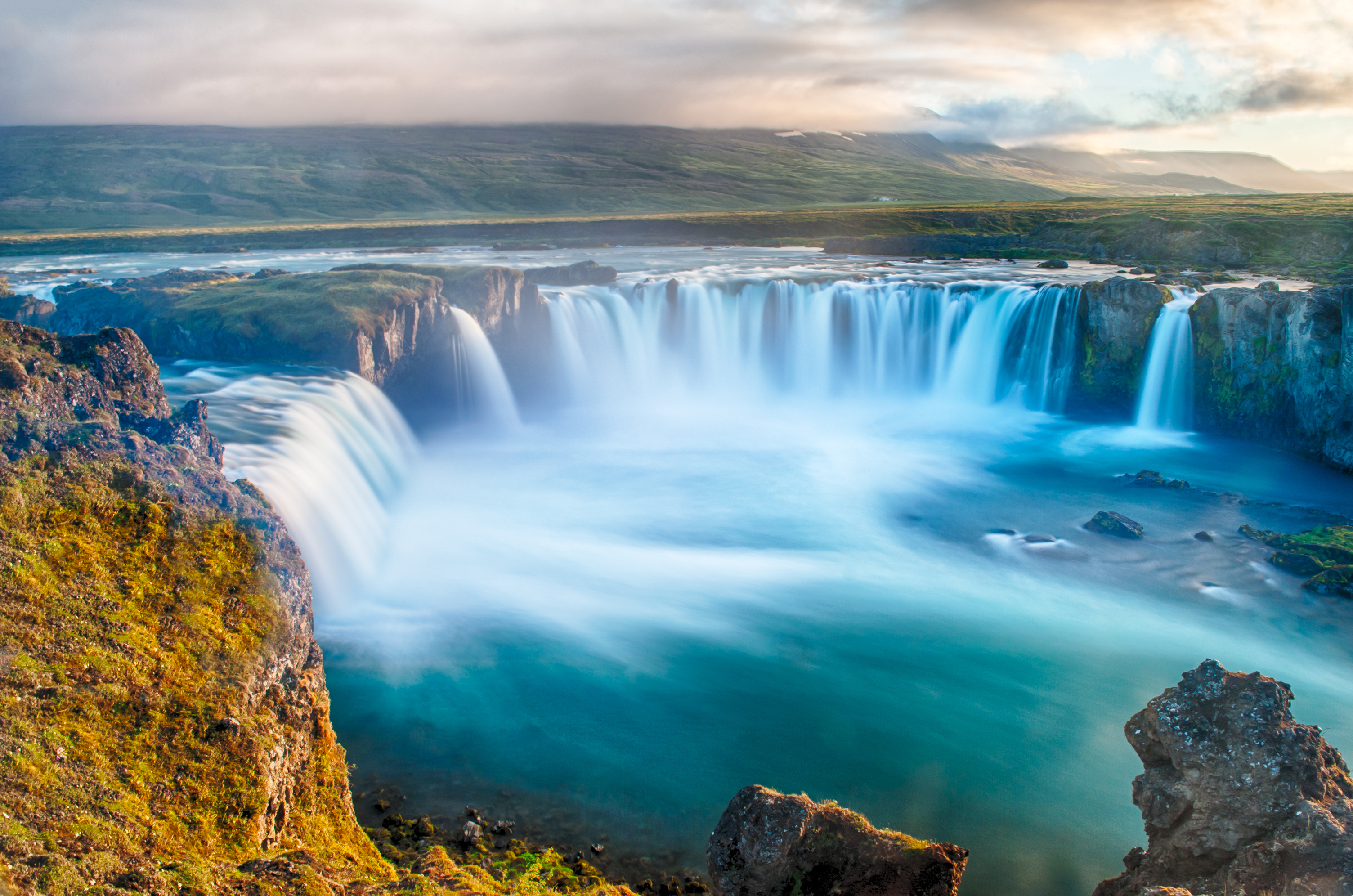 Det imponerende Godafoss vandfald i Nordisland med dramatiske vandmasser og blå nuancer fotograferet under den magiske midnatssol