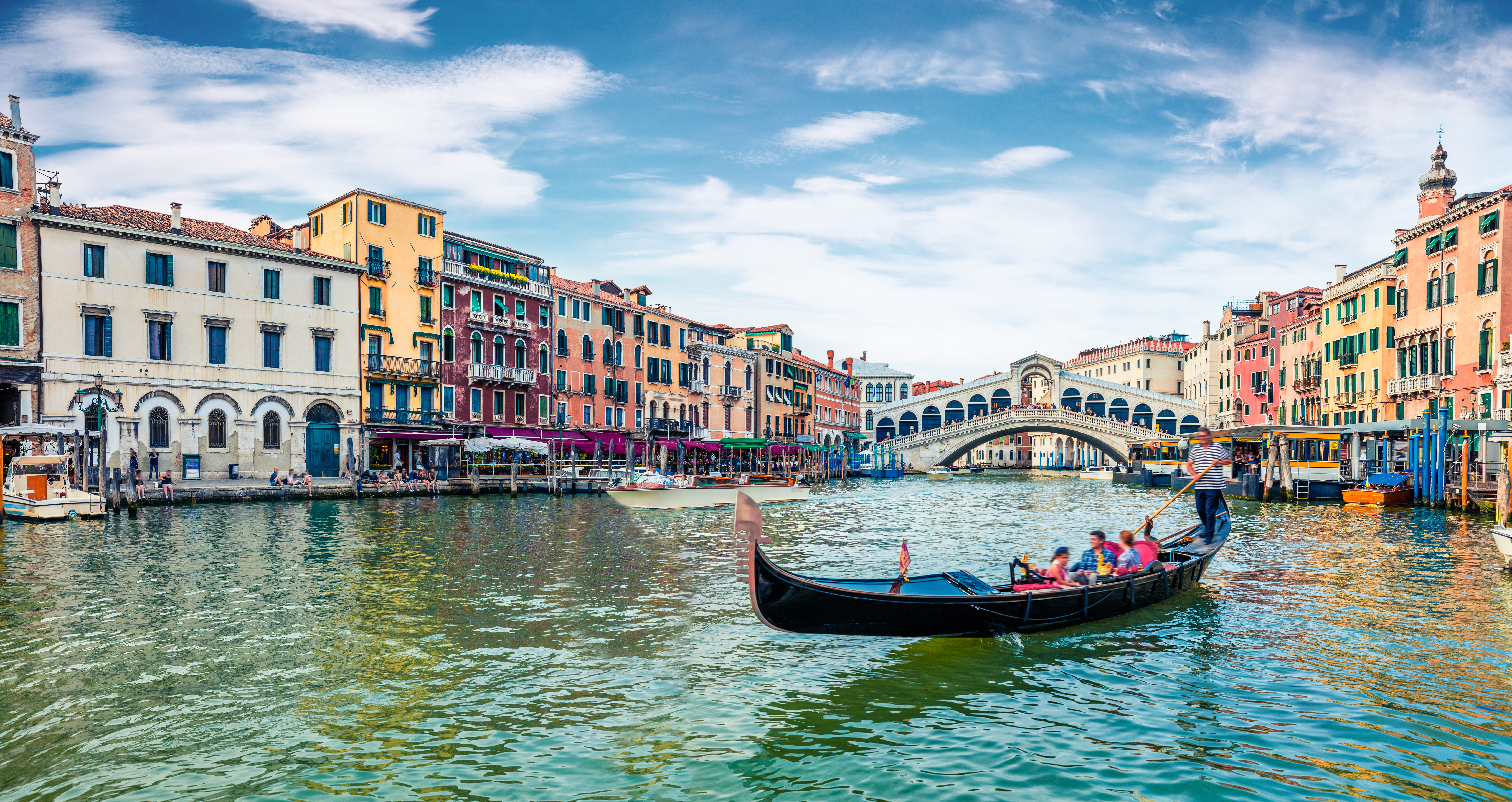 Klassisk gondoltur på Canal Grande i Venedig med udsigt til den historiske Rialto-bro og venetianske bygninger på en solrig sommerdag