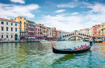 Klassisk gondoltur på Canal Grande i Venedig med udsigt til den historiske Rialto-bro og venetianske bygninger på en solrig sommerdag