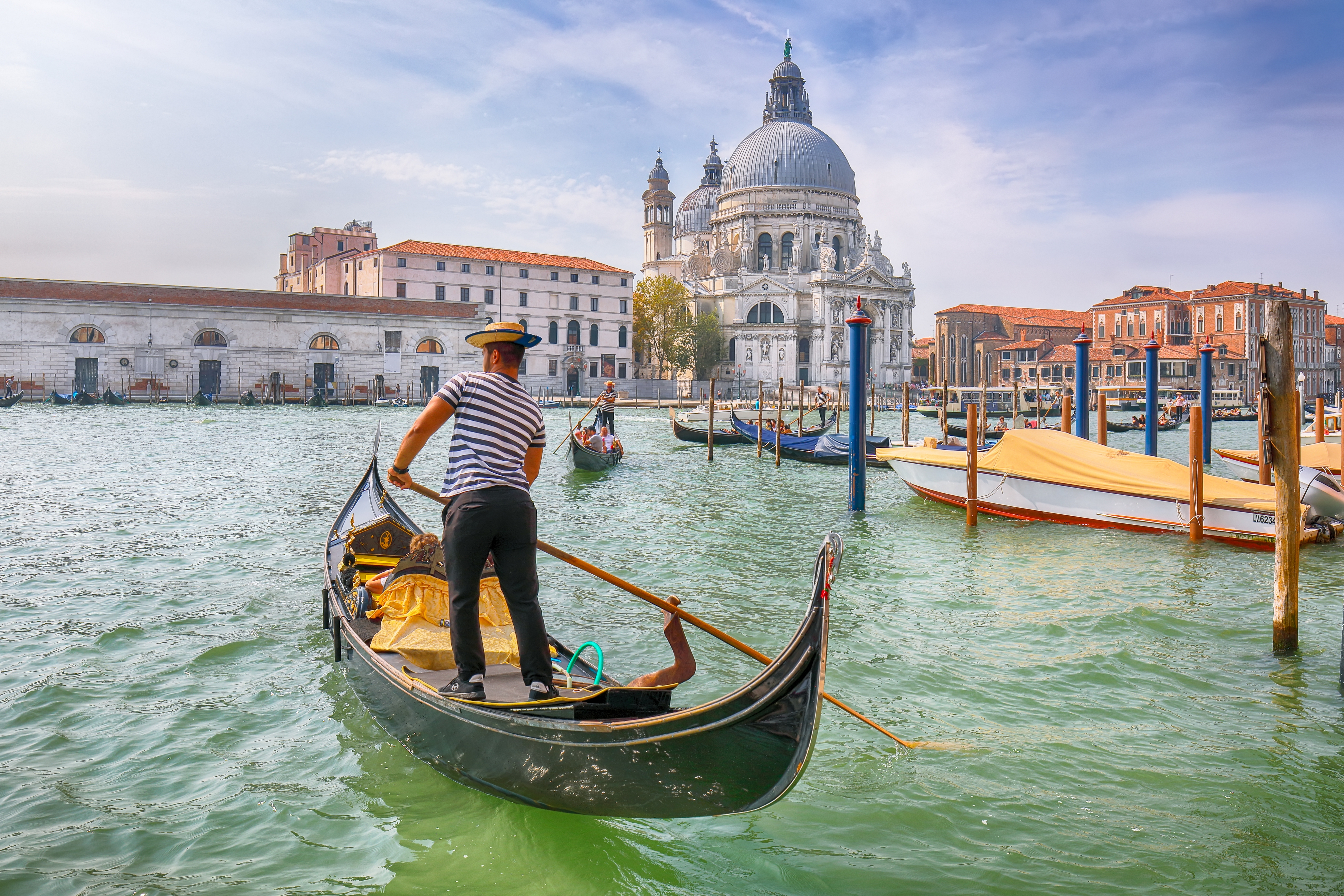 Traditionel gondoltur på Canal Grande i Venedig med den historiske Santa Maria della Salute-basilika