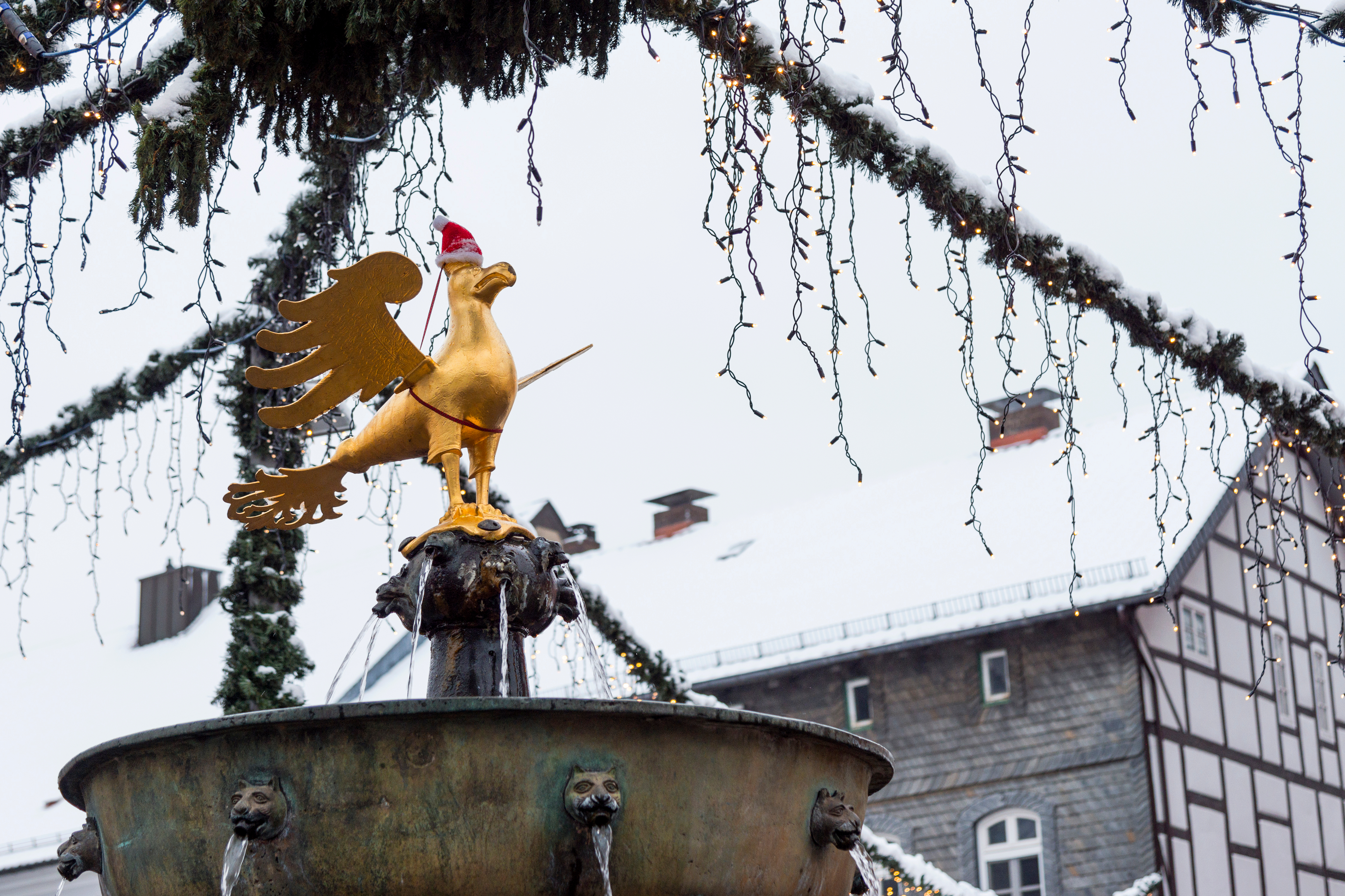 Smuk gylden kejserørn på historisk springvand i Goslar, Tyskland, dekoreret med julenissehue under julemarkedet