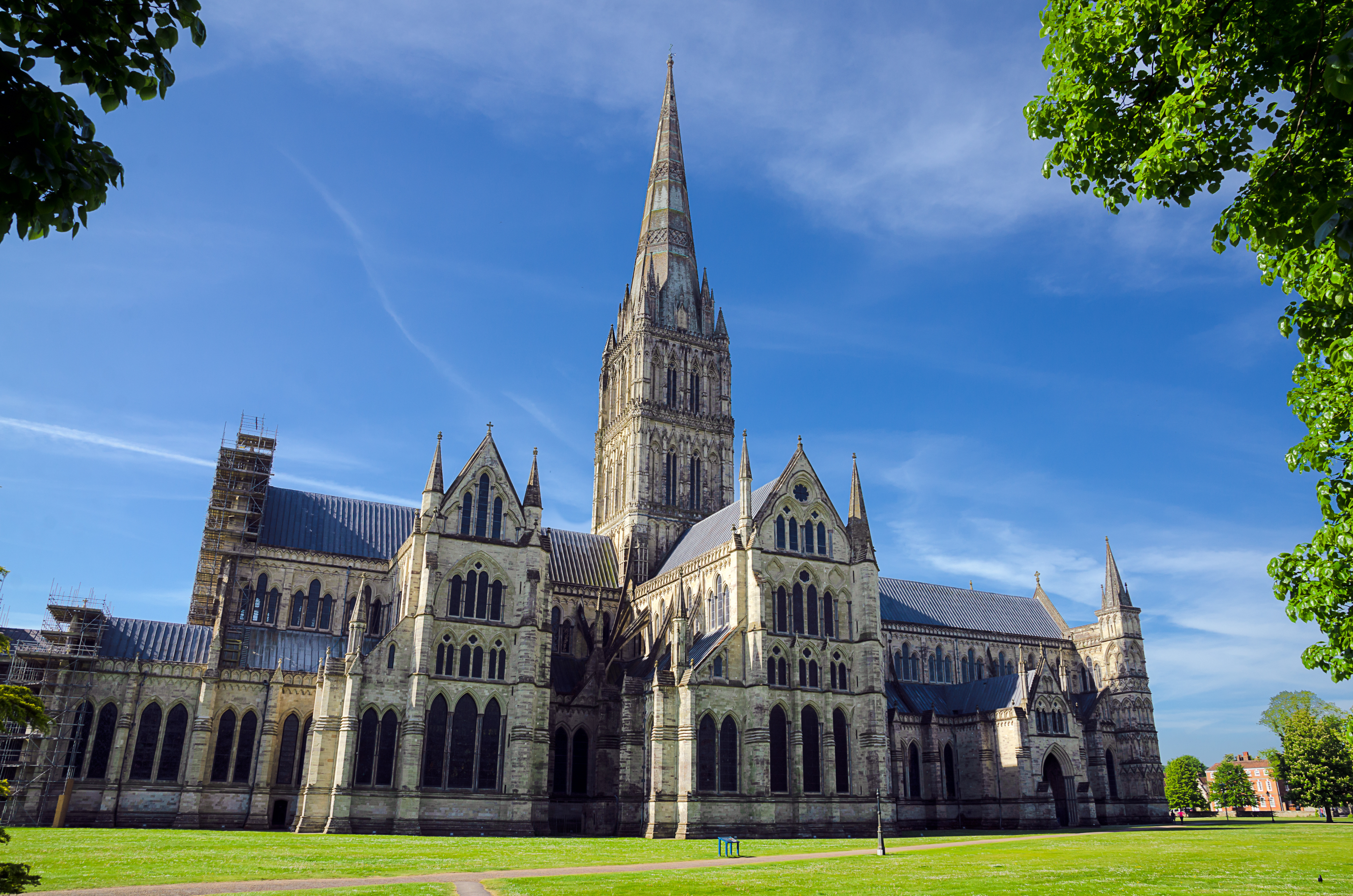Salisbury Cathedrals gotiske facade og tårn set fra de grønne omgivelser på en solrig forårsdag i England