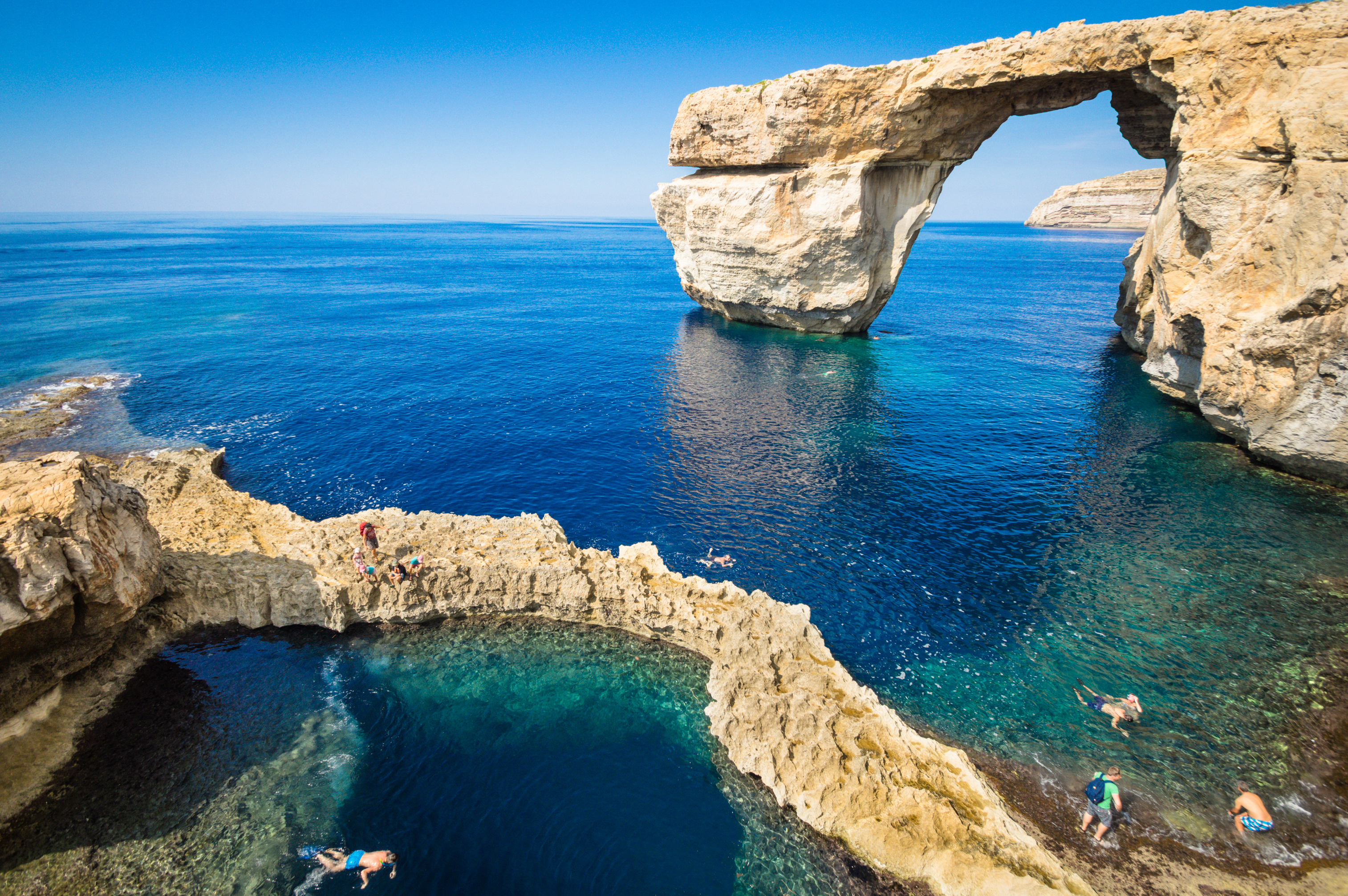 Naturlig kalkstensport på Gozo Malta med svømmere i det krystalklare middelhavsvand