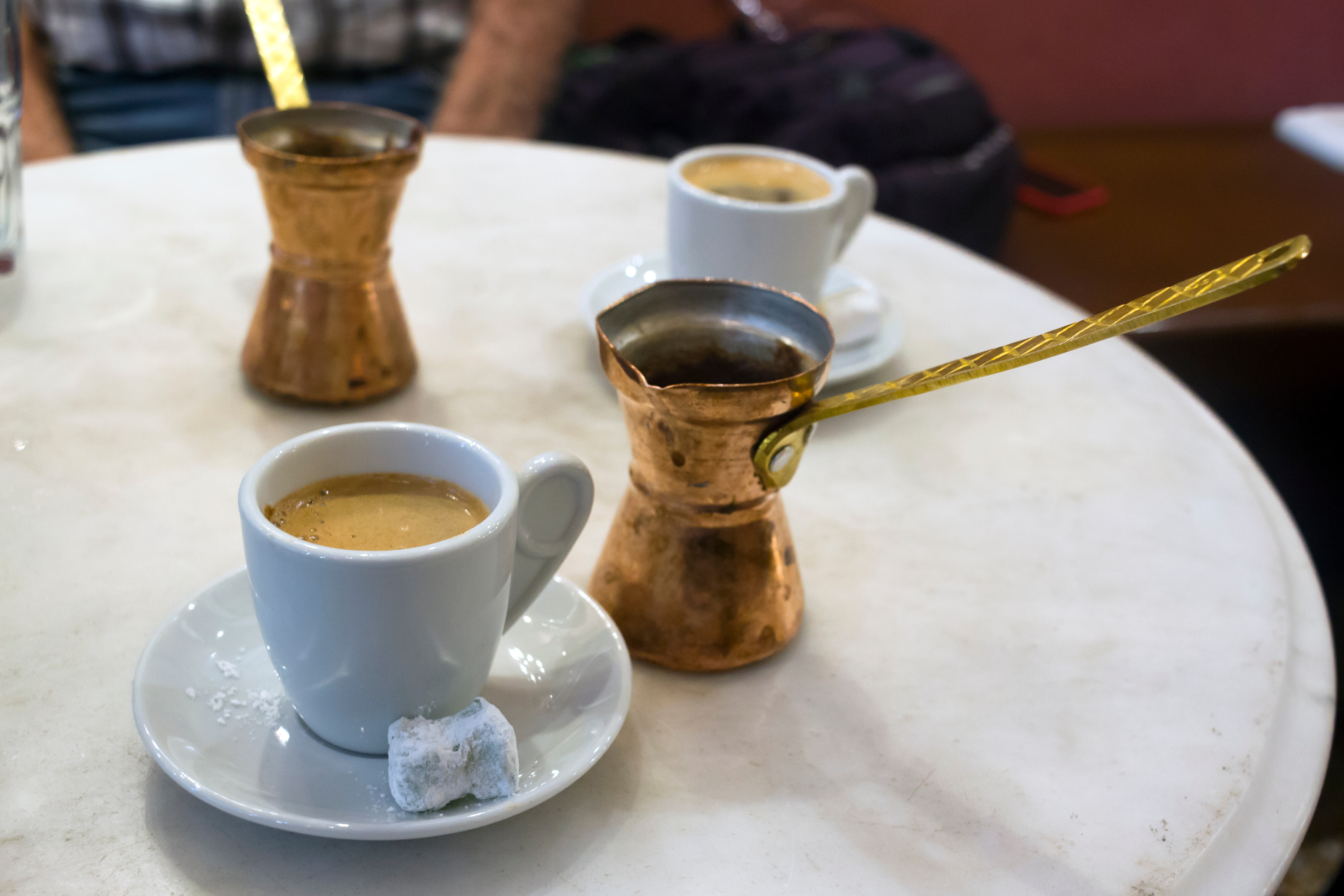 Traditionel græsk kaffe serveret med kobber kaffekande og søde loukoumi stykker på marmorbord i Athen