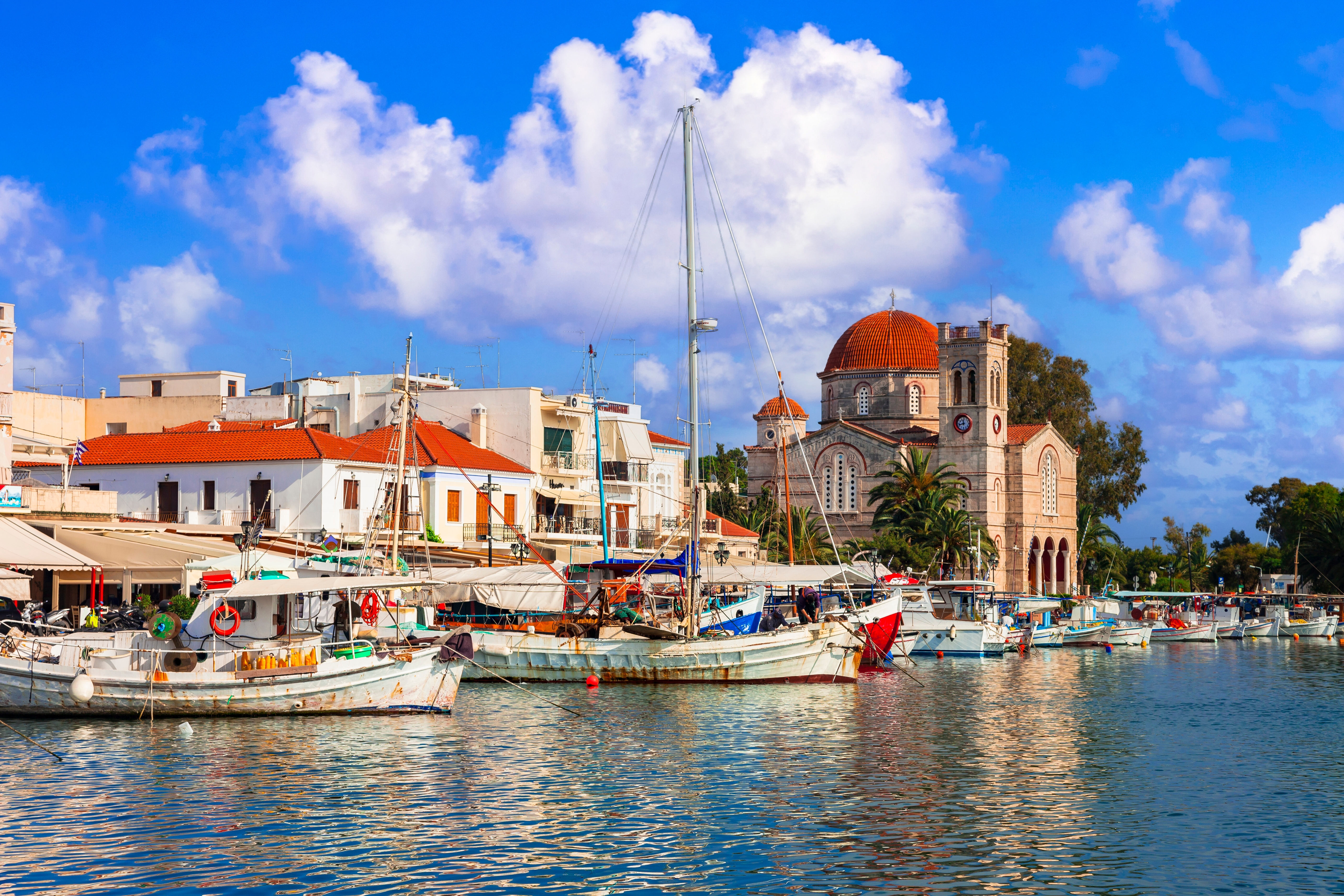 Idyllisk græsk fiskelandsby på Aegina med hvide huse og blåt hav under sommerhimmel