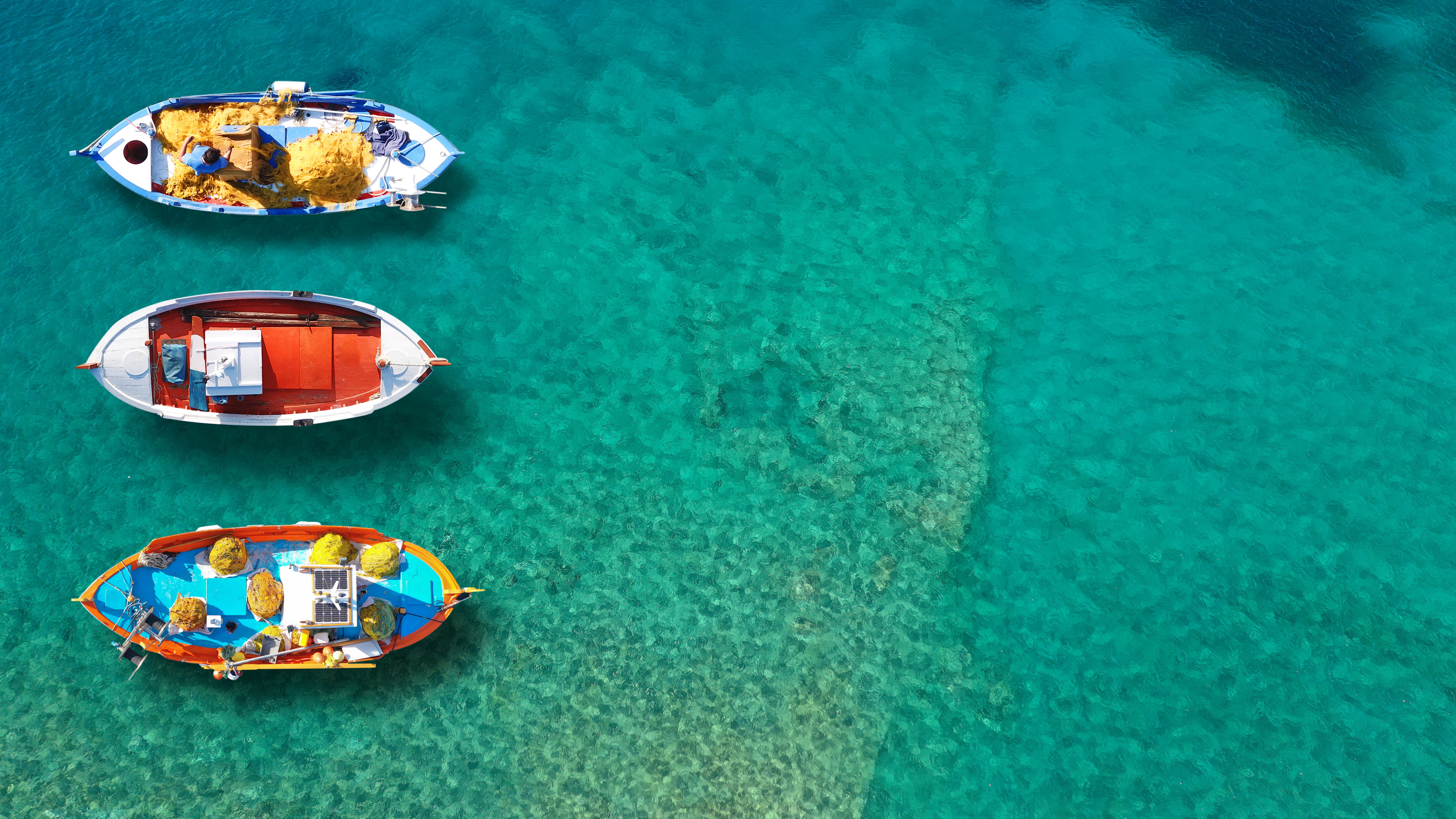 Luftfoto af traditionelle græske både i det azurblå vand ved Spetses