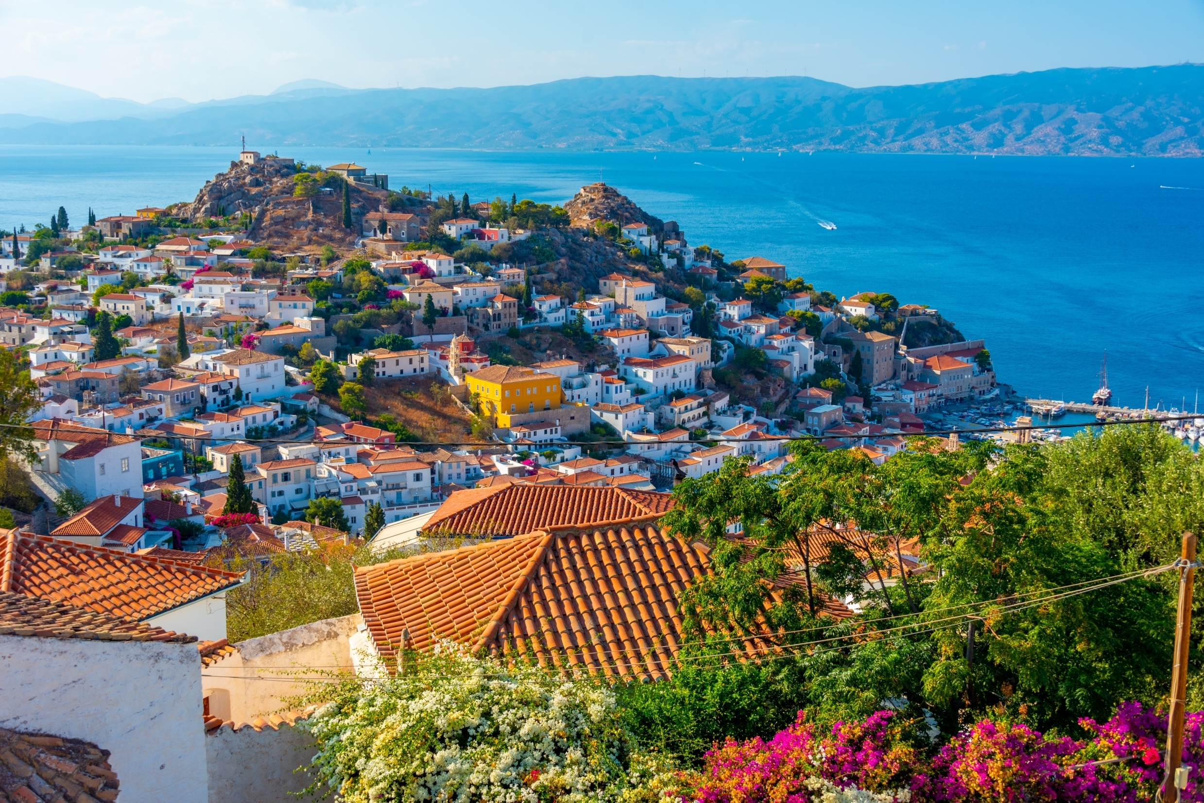 Smuk udsigt over Hydra øen i Grækenland med hvide huse, farverige blomster og krystalklart blåt vand