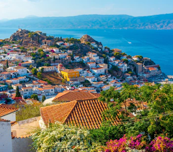 Smuk udsigt over Hydra øen i Grækenland med hvide huse, farverige blomster og krystalklart blåt vand