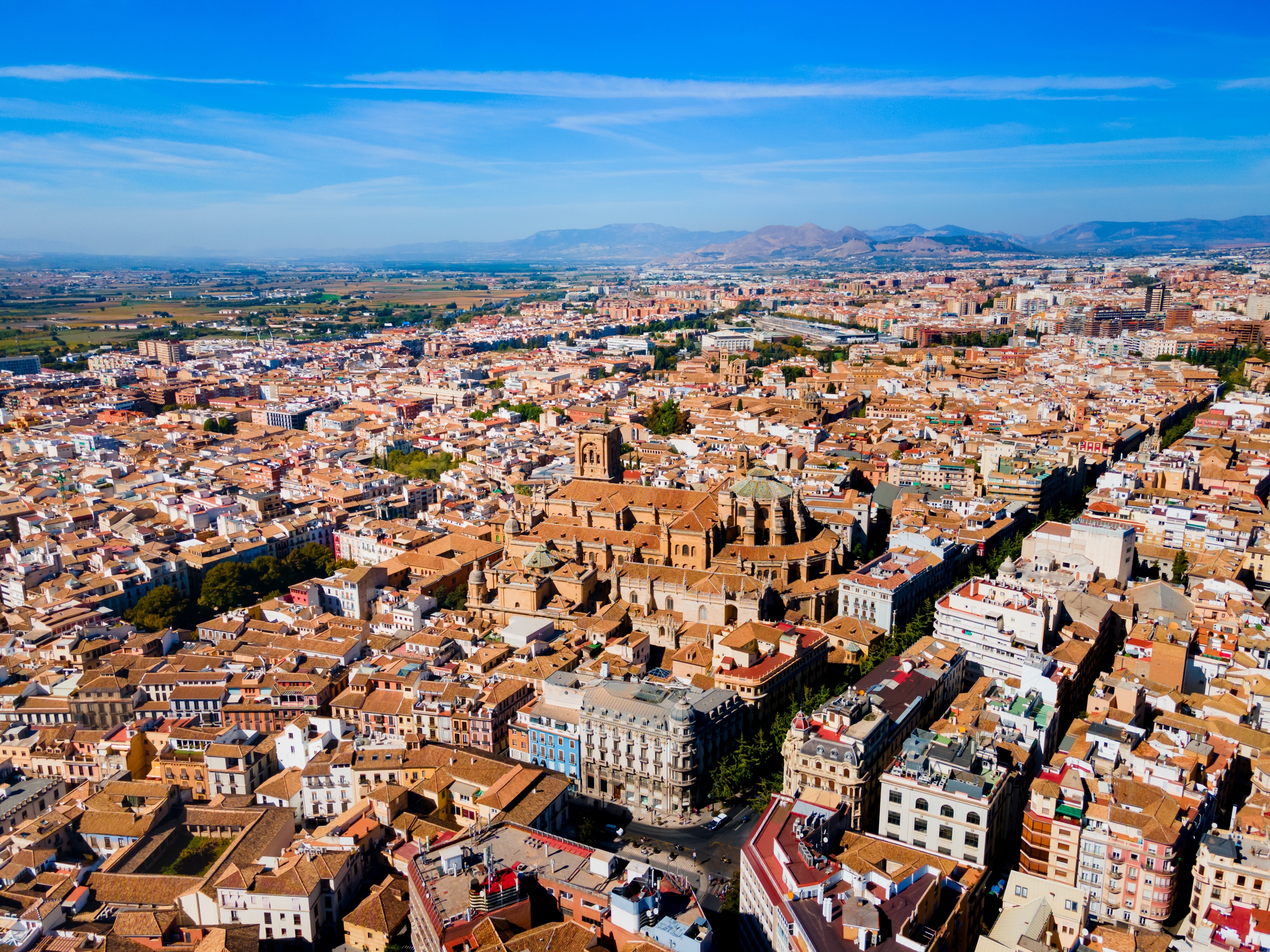 Dronefotos over Granadas katedral og den gamle bydel i Granada, Andalusien, Spanien, med karakteristiske røde tage og Sierra Nevada i horisonten