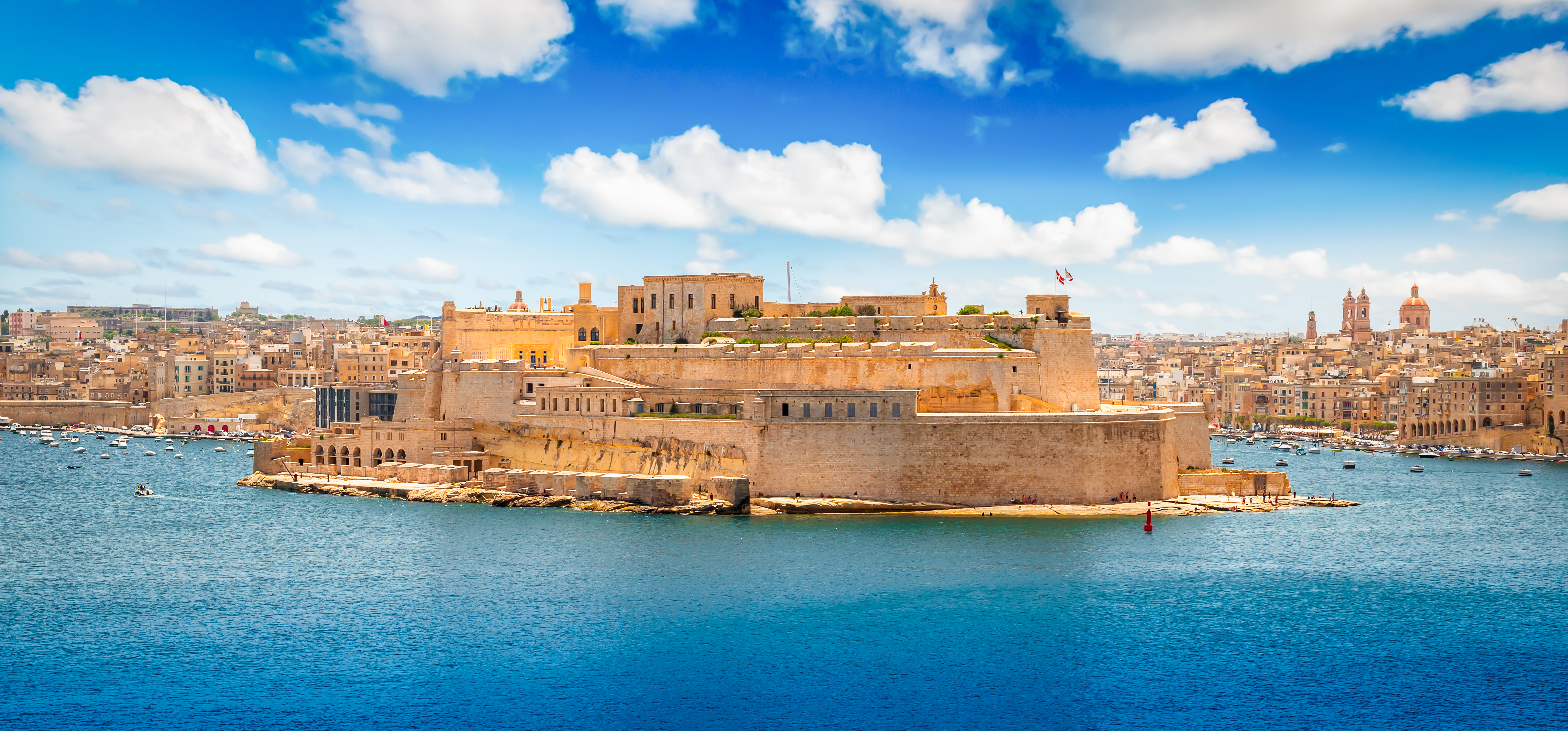 Den majestætiske fæstning ved Grand Harbour i Valletta, Maltas smukke hovedstad, med blåt hav og idyllisk bylandskab