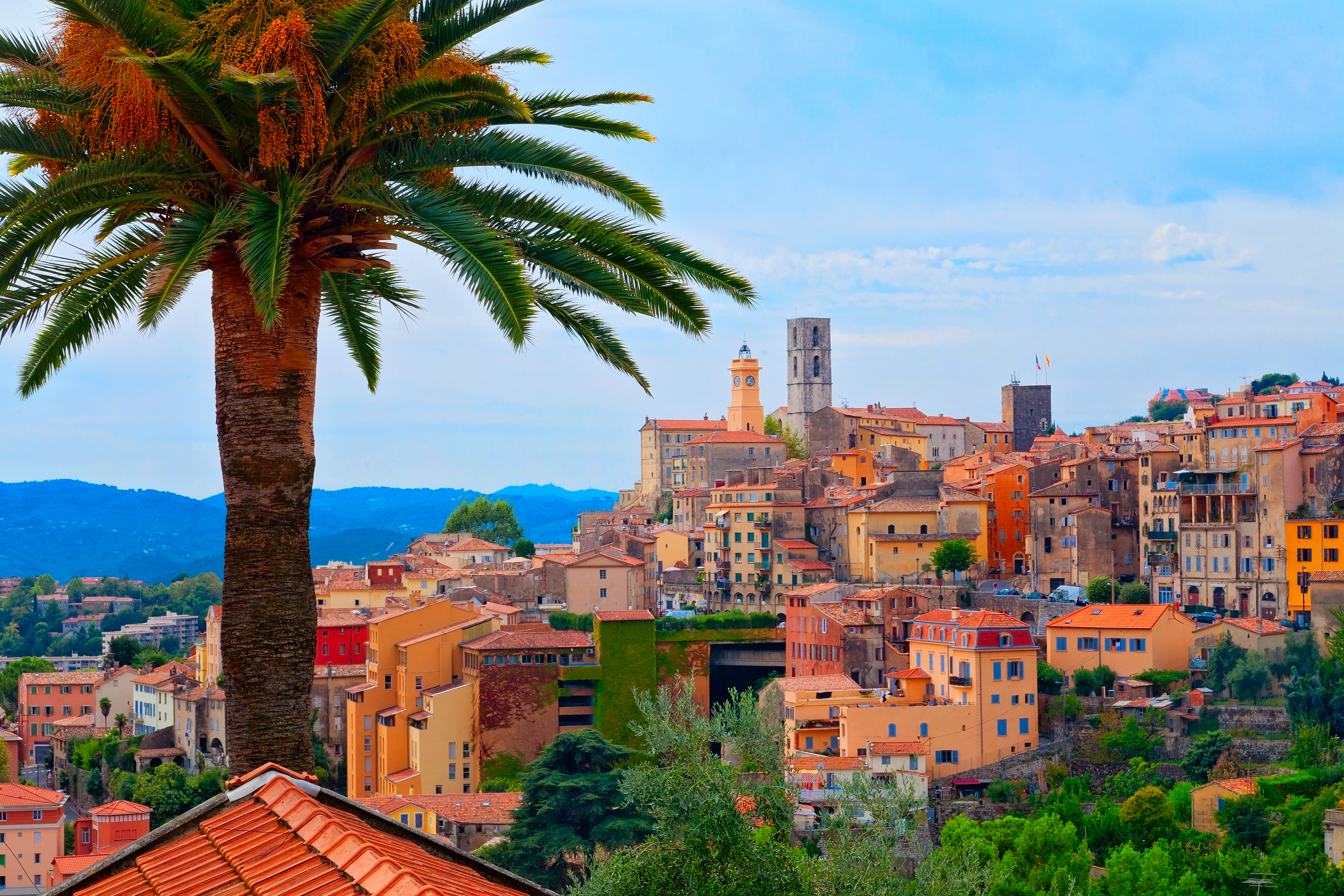 Historisk bymidte i Grasse på den Franske Riviera med farverige mediterrane bygninger og palme i forgrunden