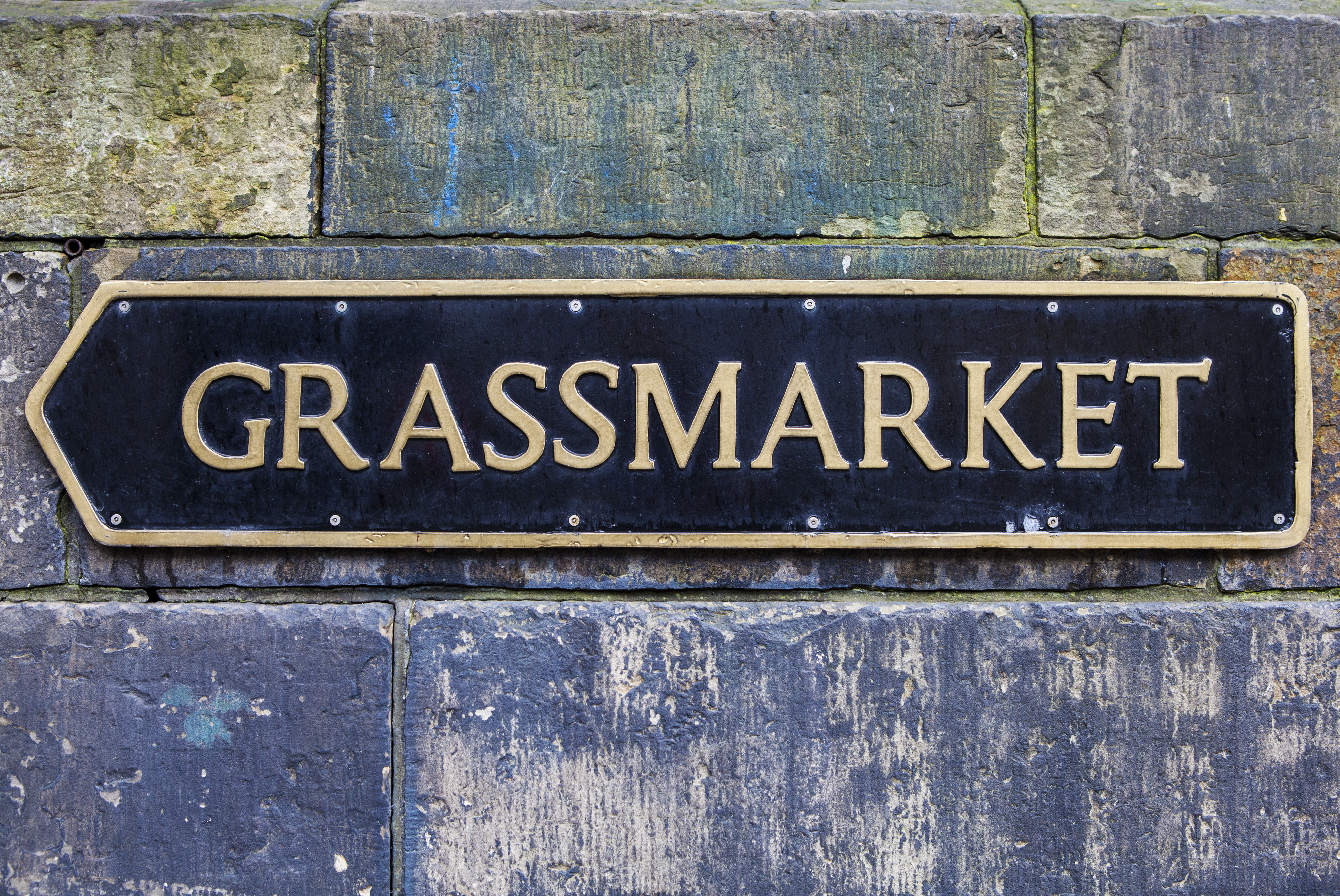 Elegant sort og guld gadeskilt til Grassmarket på historisk stenmur i Edinburgh, Skotland