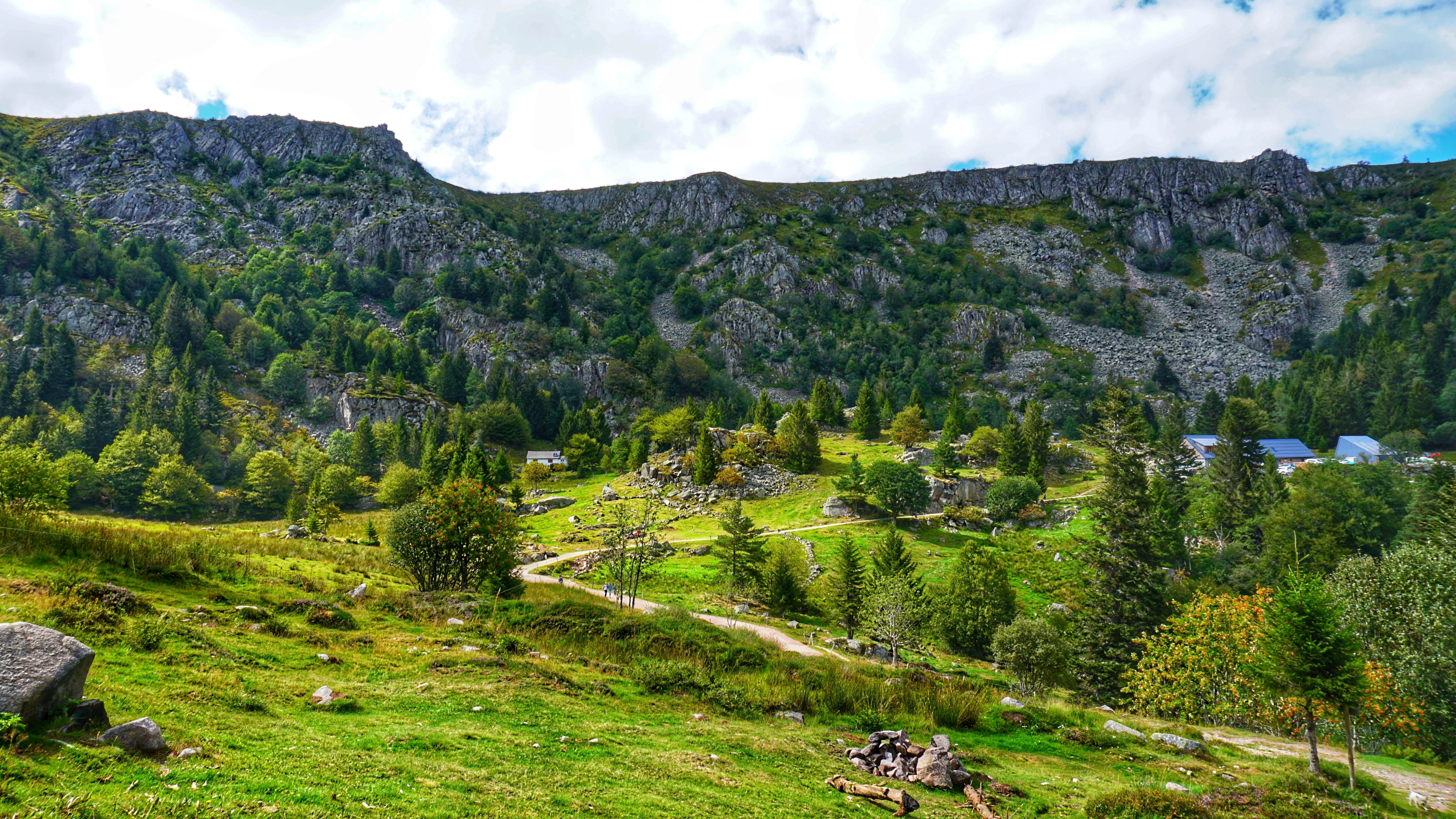 Grøn bjergdal med vandreruter gennem frodig natur og skovbevoksede skråninger