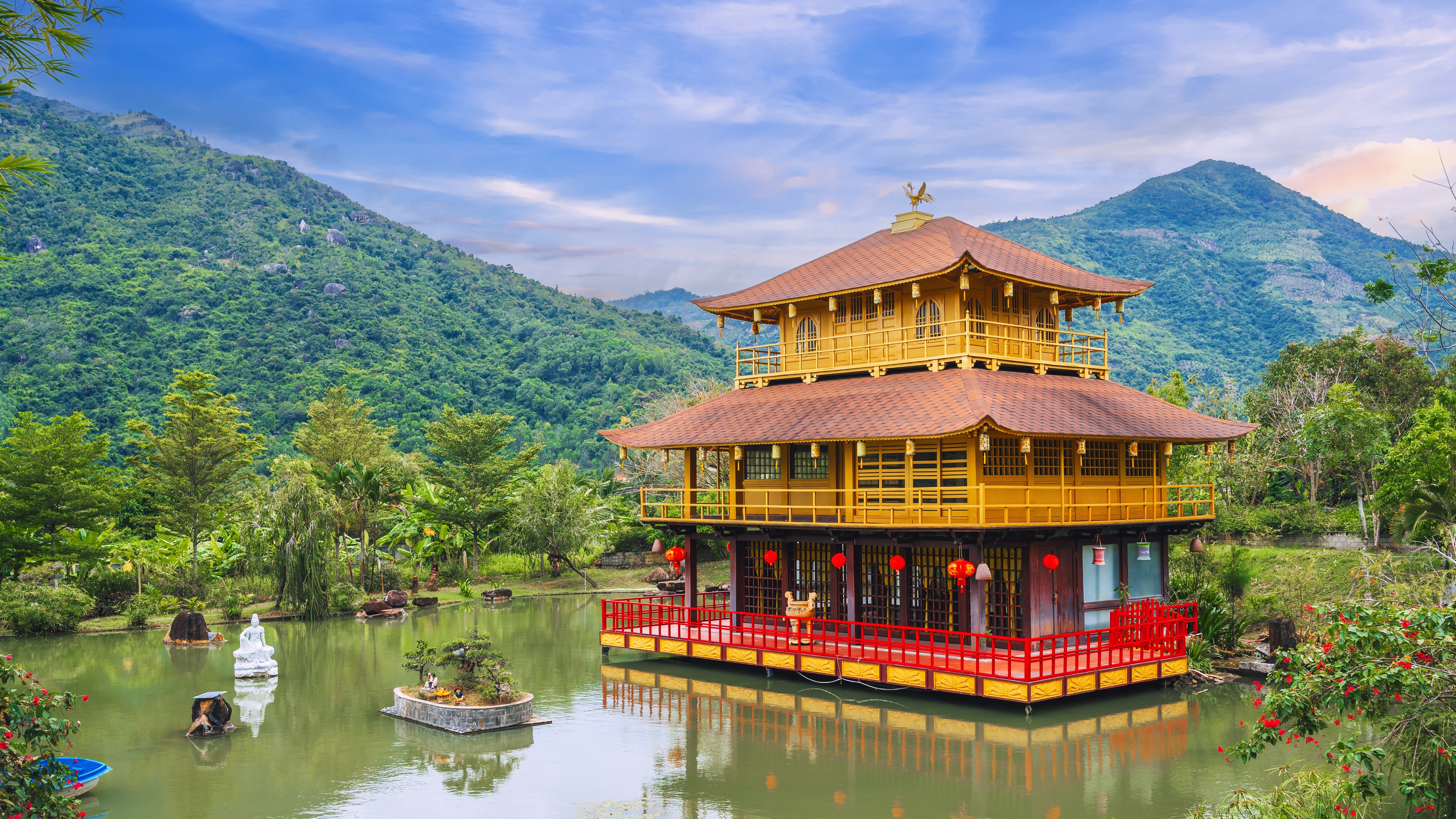 Flot gyldent pagode-tempel omgivet af tropisk natur og bjerge ved den rolige sø i Nha Trang, Vietnam