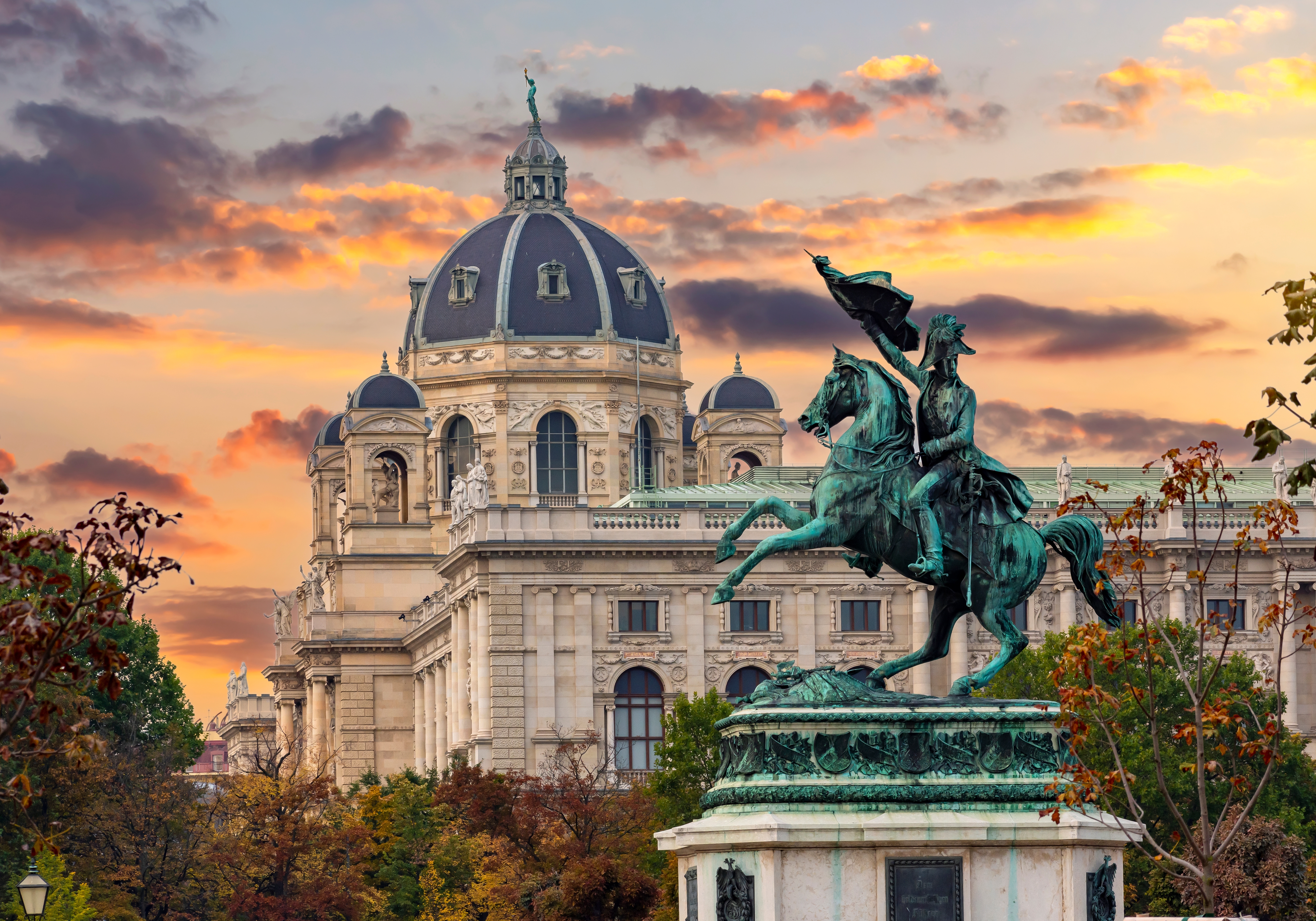 Habsburgsk ryttermonument af Ærkehertug Karl på Heldenplatz med Kunsthistorisches Museums kuppel i baggrunden under en farverig solnedgang i Wien