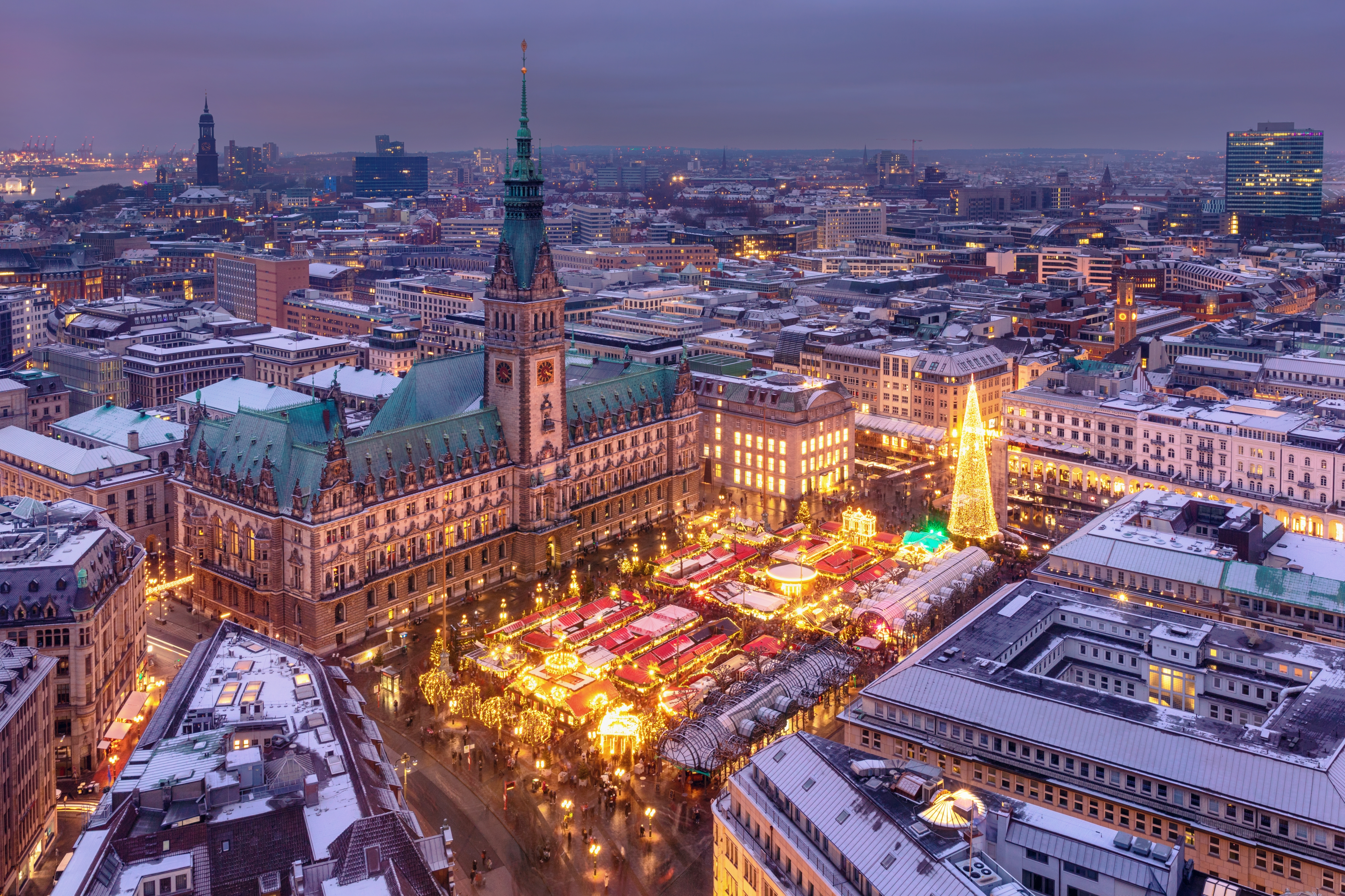 Stemningsfuldt luftfoto af julemarkedet ved Hamburgs rådhus på Rathausmarkt med oplyste boder og juletræ om aftenen