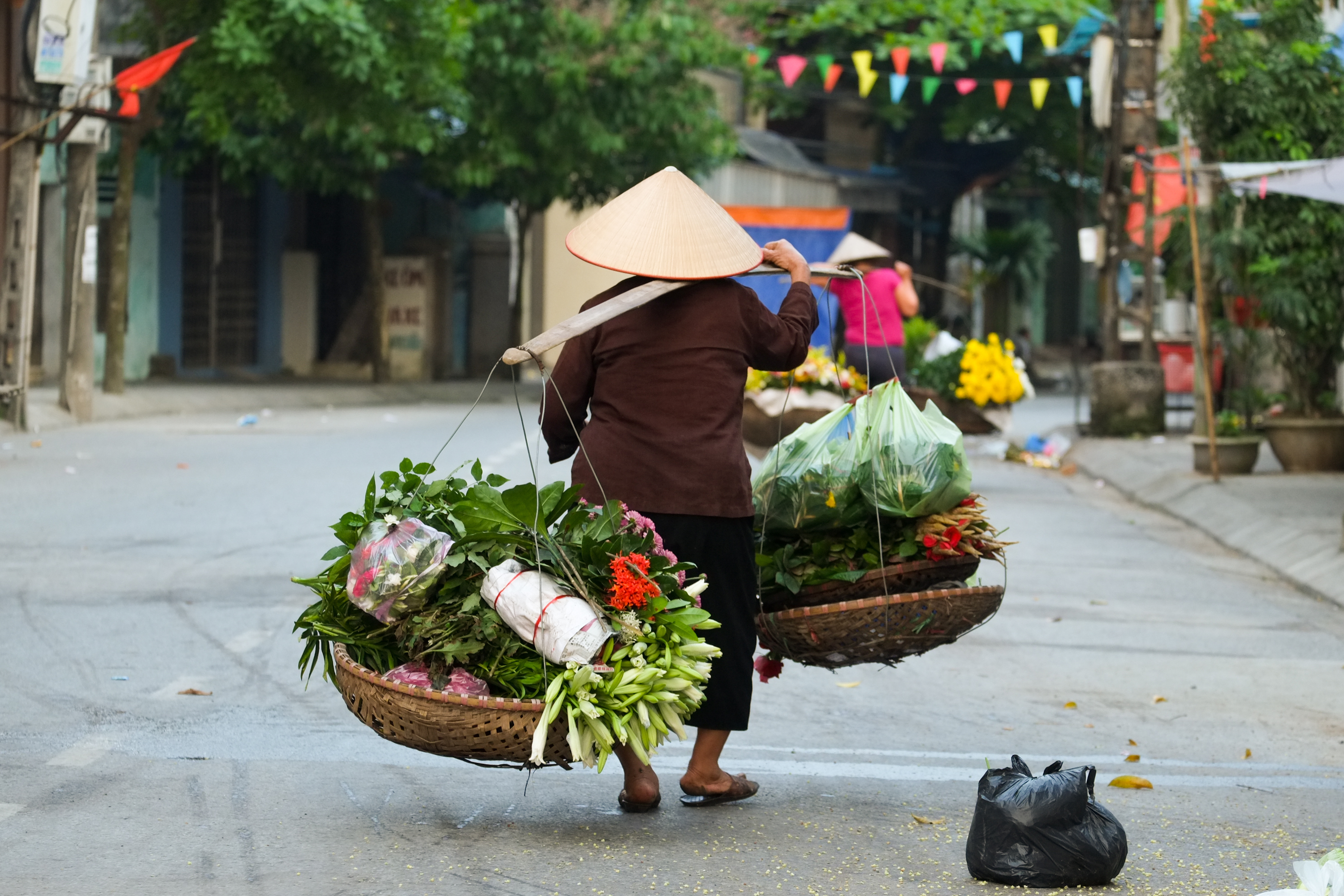 Traditionel vietnamesisk sælger med blomster og lokale produkter på gaden
