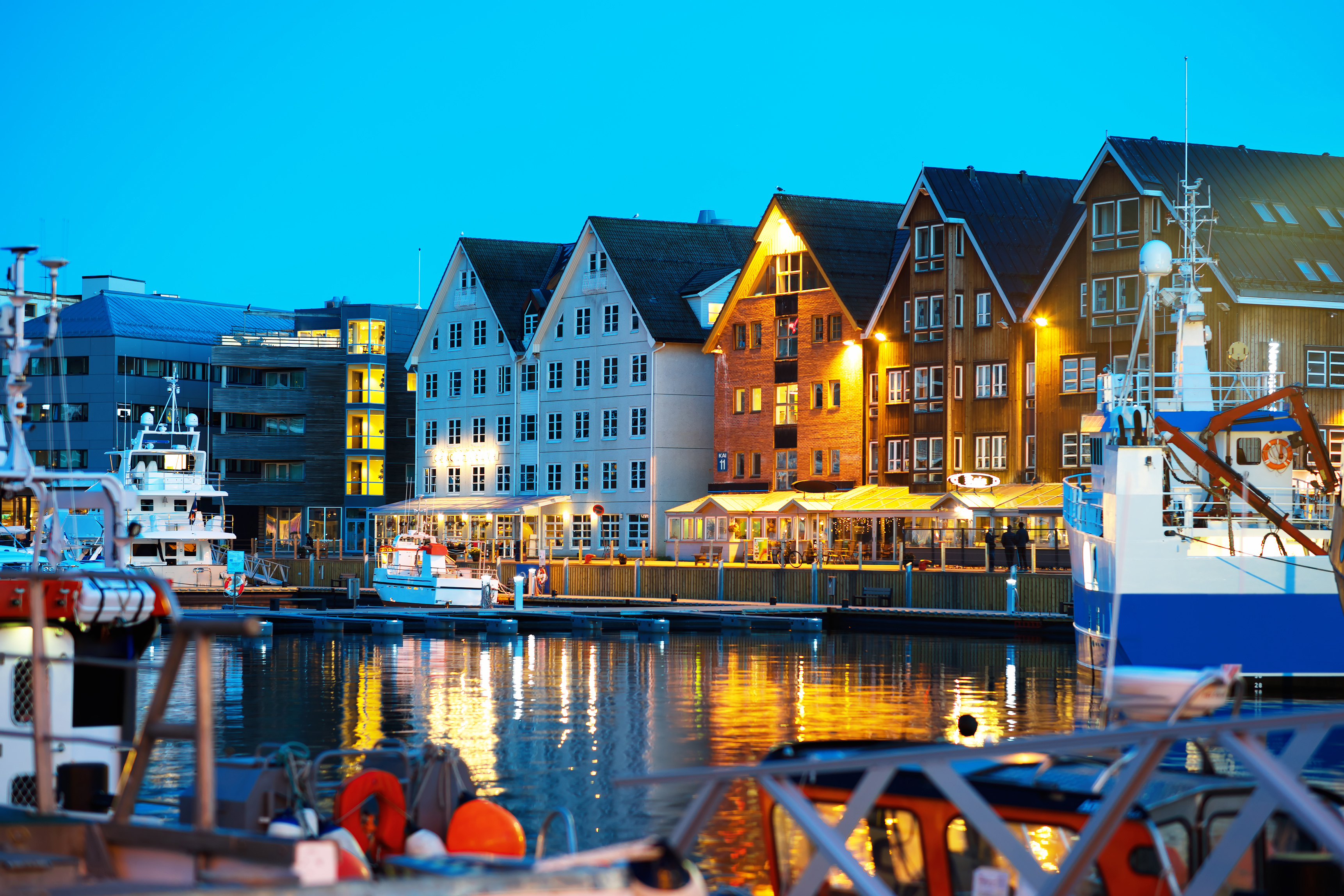 Historiske havnehuse langs vandet med fiskerbåde i skandinavisk havneby