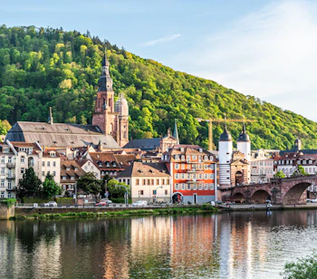 Malerisk udsigt over Heidelbergs gamle by med historisk bro, kirketårne og traditionelle tyske huse ved Neckar-floden