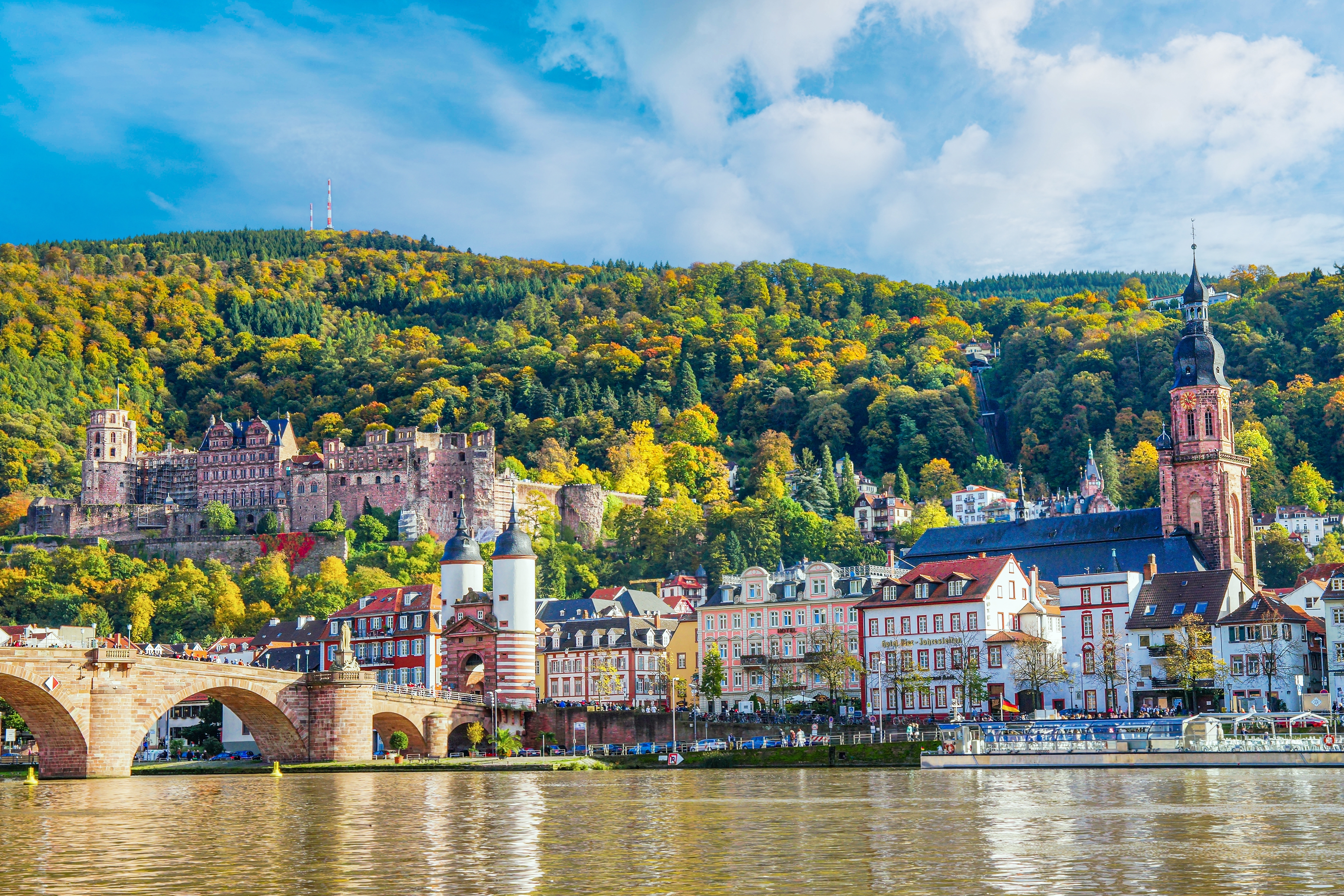 Idyllisk udsigt over Heidelberg Slot og den gamle stenbro Alte Brücke over Neckar-floden med farverig efterårsskov i baggrunden, Tyskland