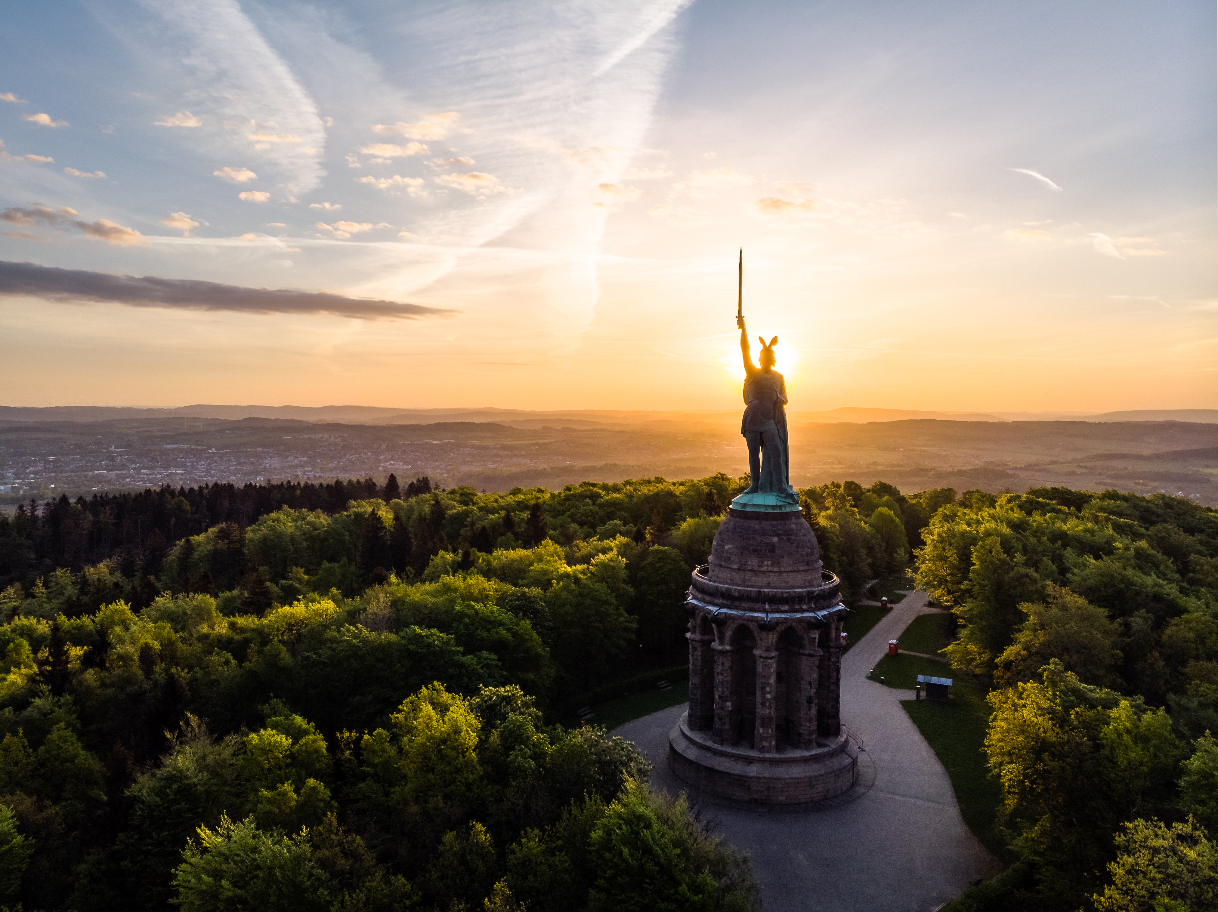 Hermannsdenkmal krigermonumentet i Teutoburger Wald set fra luften ved solnedgang med gyldent lys og grøn skov rundt om
