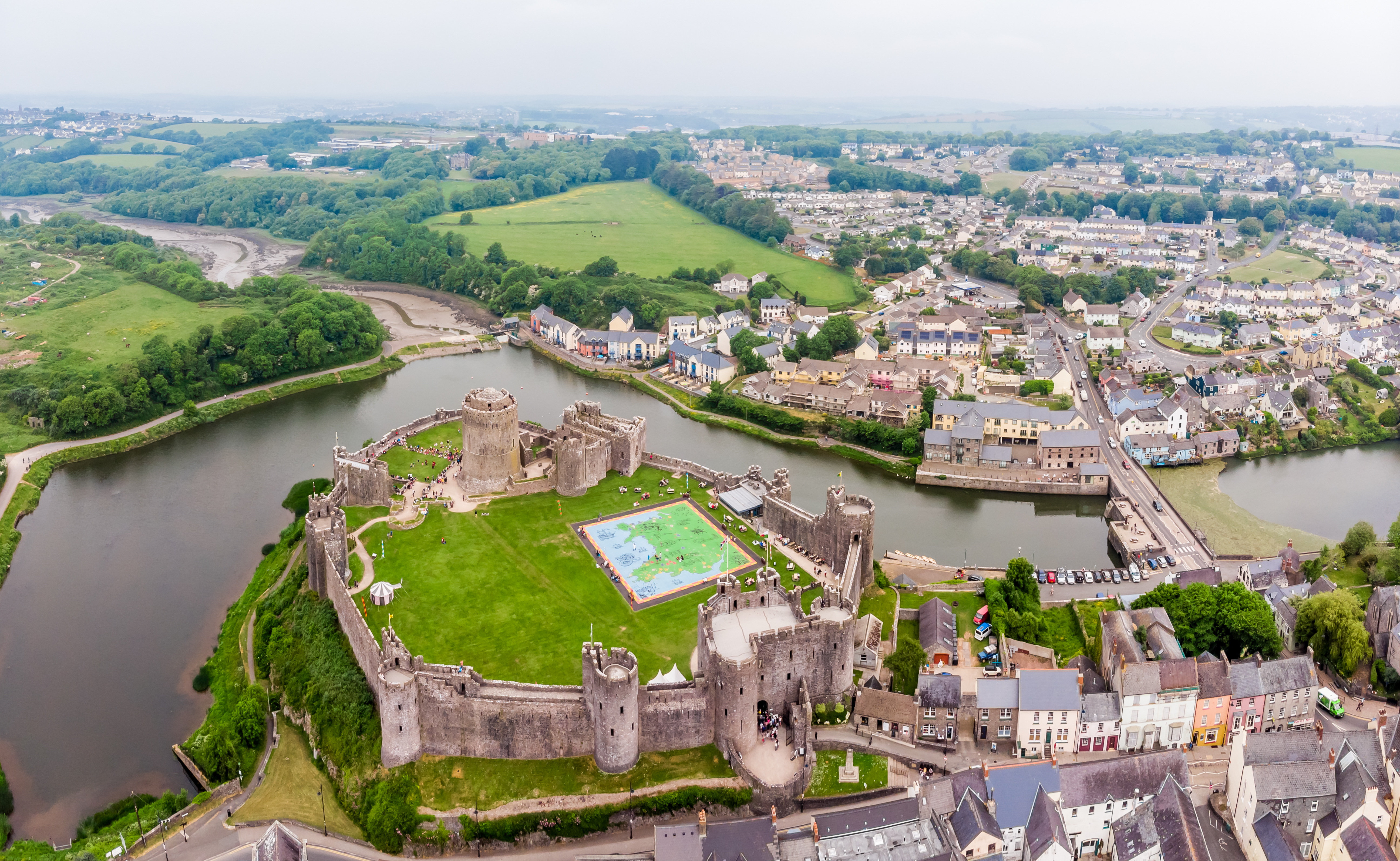 Historisk Pembroke Slot i Wales set fra luften med middelalderlige mure og tårne ved floden