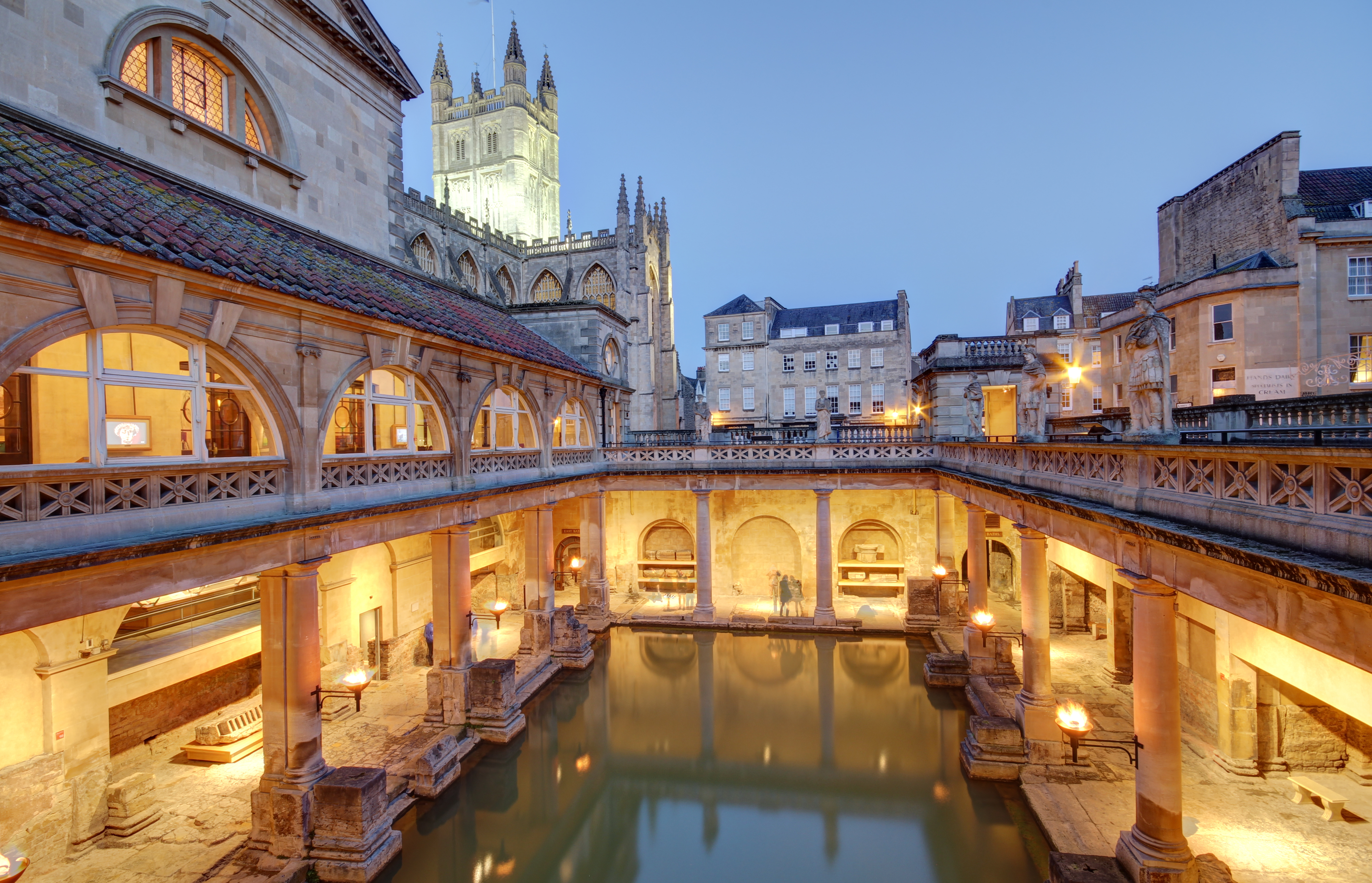 De smukt bevarede historiske romerske termer i Bath, England, fotograferet i aftenlys med den ikoniske pool og de klassiske søjler, der skaber en magisk atmosfære