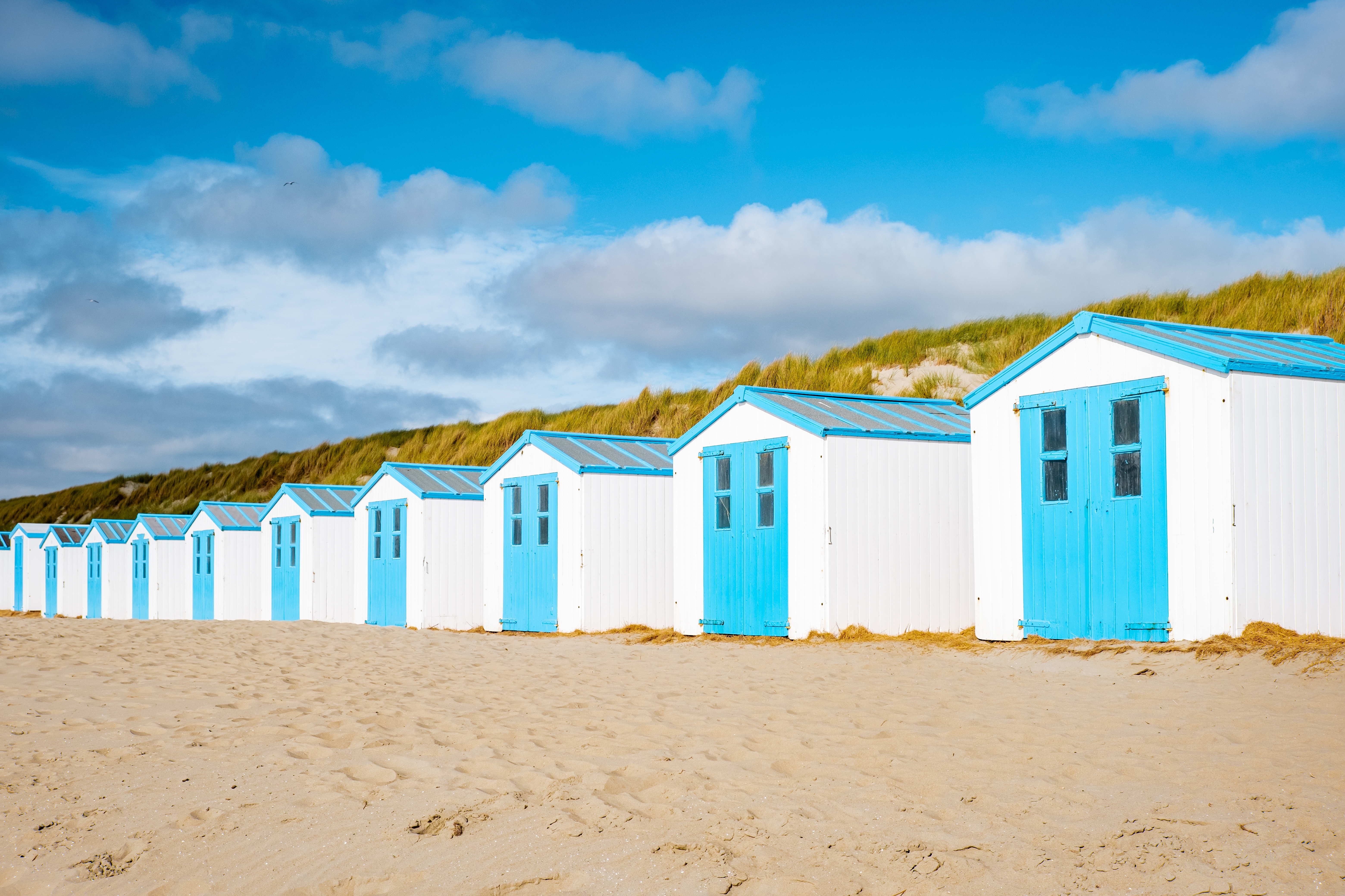Farverige hvide og blå strandhytter på stranden ved De Koog på Texel i Holland med smuk blå himmel