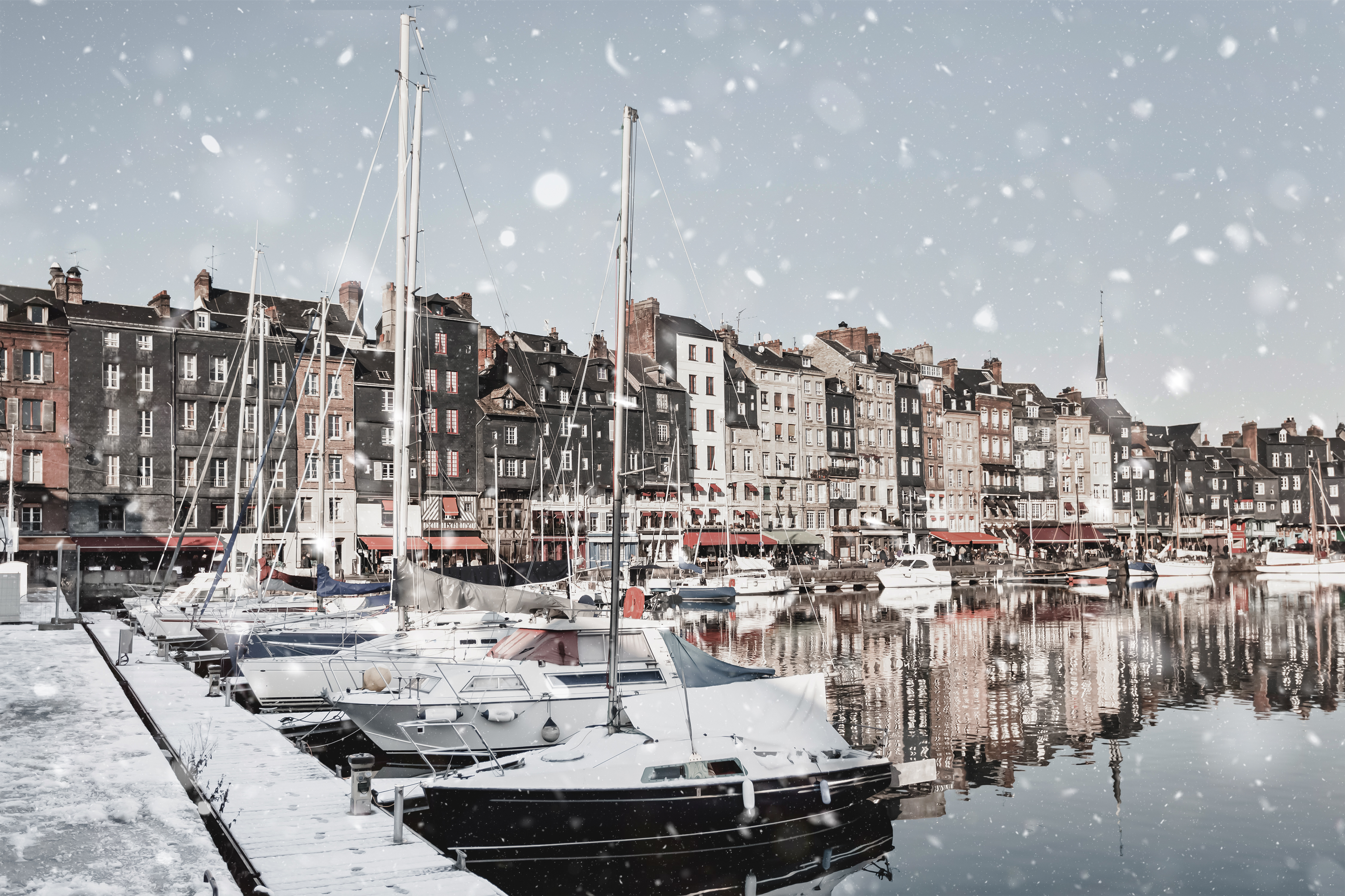 Honfleur i Normandiet, Frankrig med smuk snestorm over havnen og historiske bygninger spejlet i det rolige havnevand