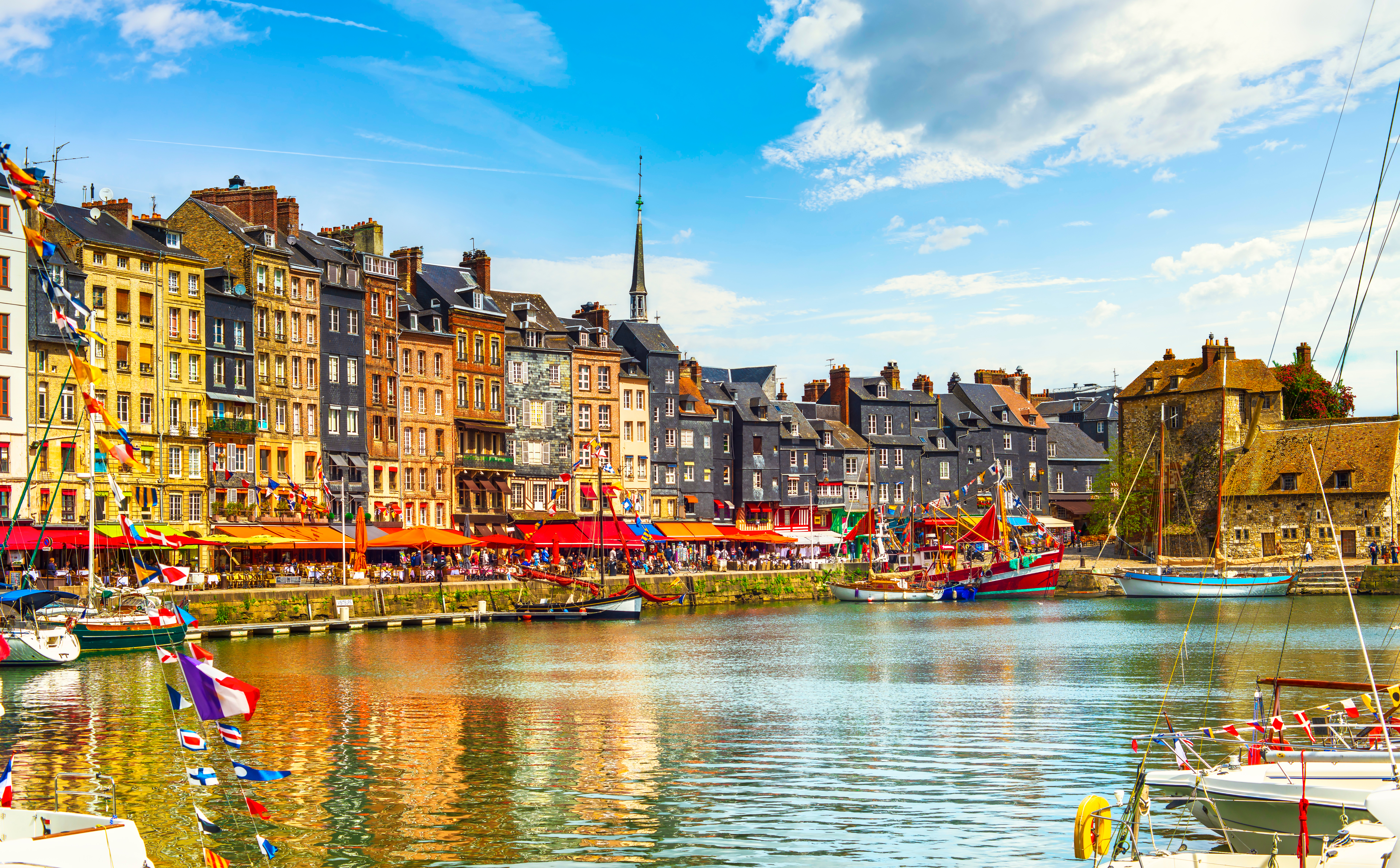 Sejlbåde og farverige facader ved den historiske havn i Honfleur