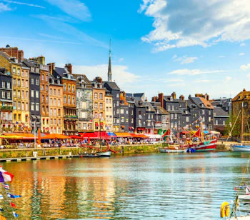 Sejlbåde og farverige facader ved den historiske havn i Honfleur
