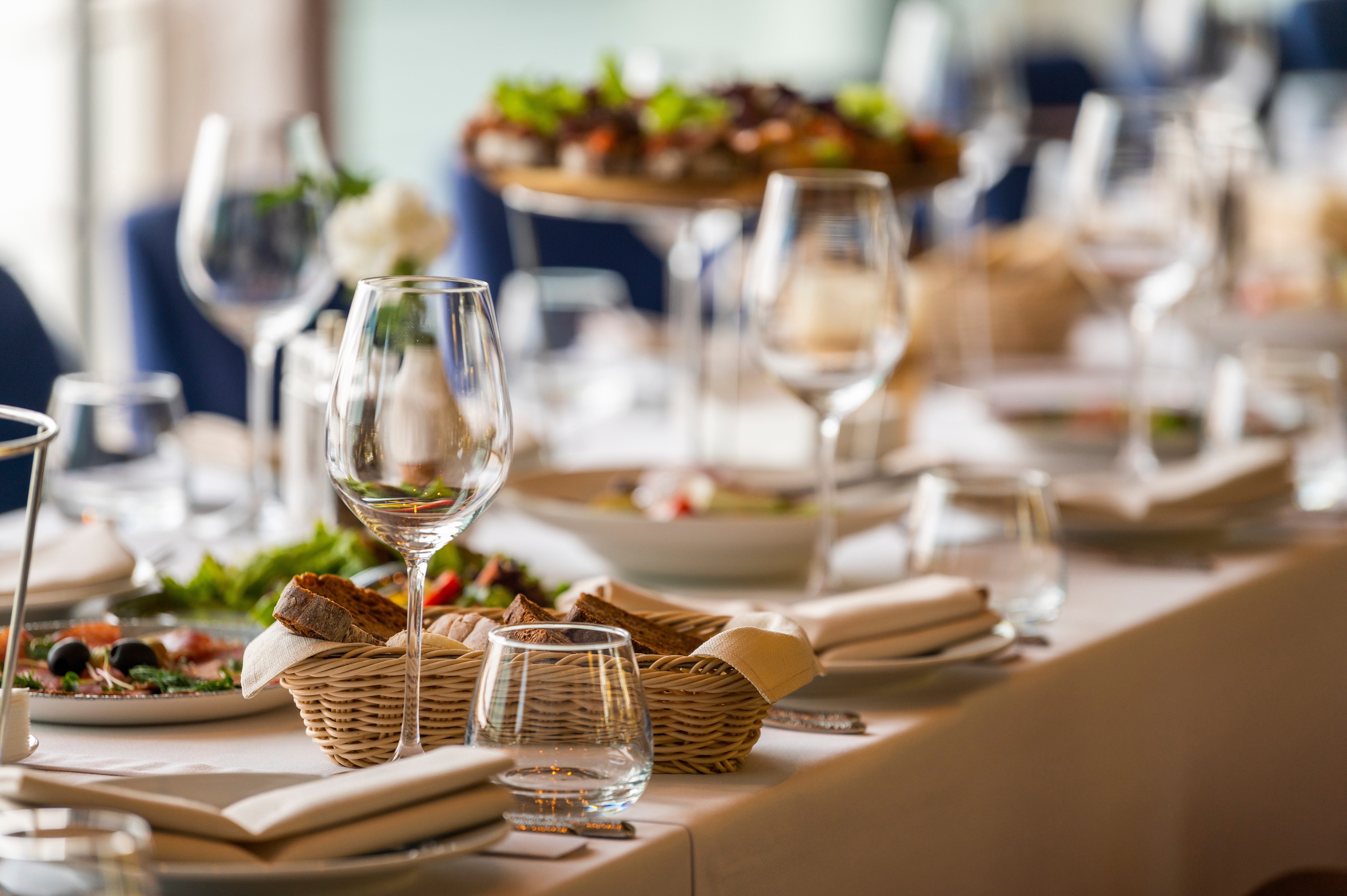 Elegant borddækning på Hotel Bisesti med hvid dug, vinglas og brødkurv til den inkluderede 3-retters aftenmenu på halvpension