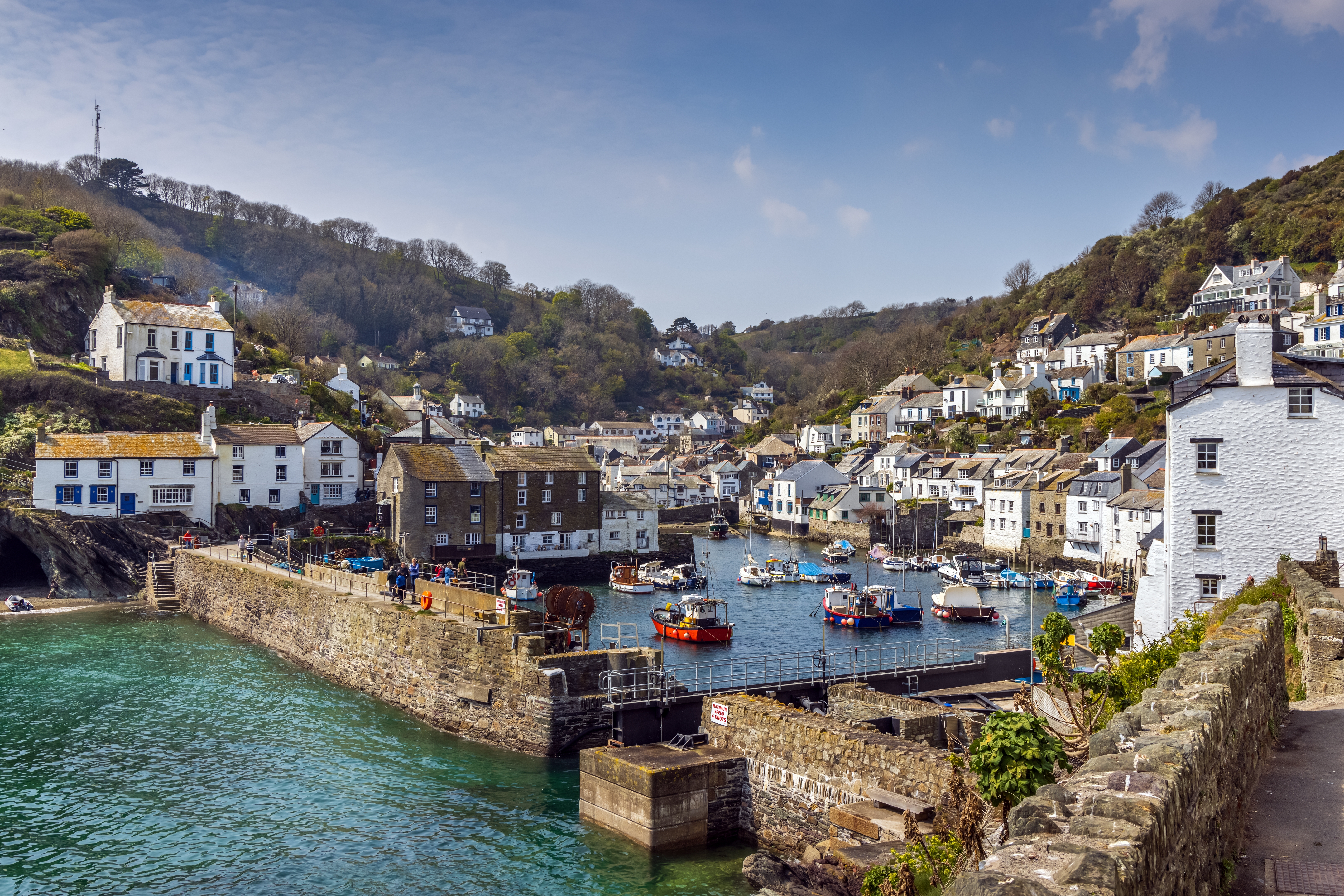 Hyggelig udsigt over den pittoreske fiskerihavn i Polperro med traditionelle engelske huse og ankrede både på en skøn sommerdag i Cornwall