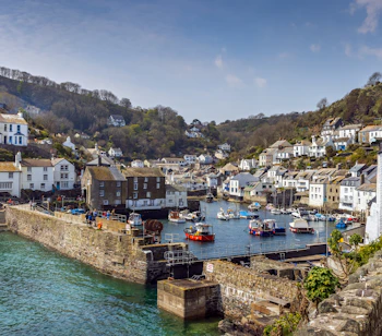 Hyggelig udsigt over den pittoreske fiskerihavn i Polperro med traditionelle engelske huse og ankrede både på en skøn sommerdag i Cornwall