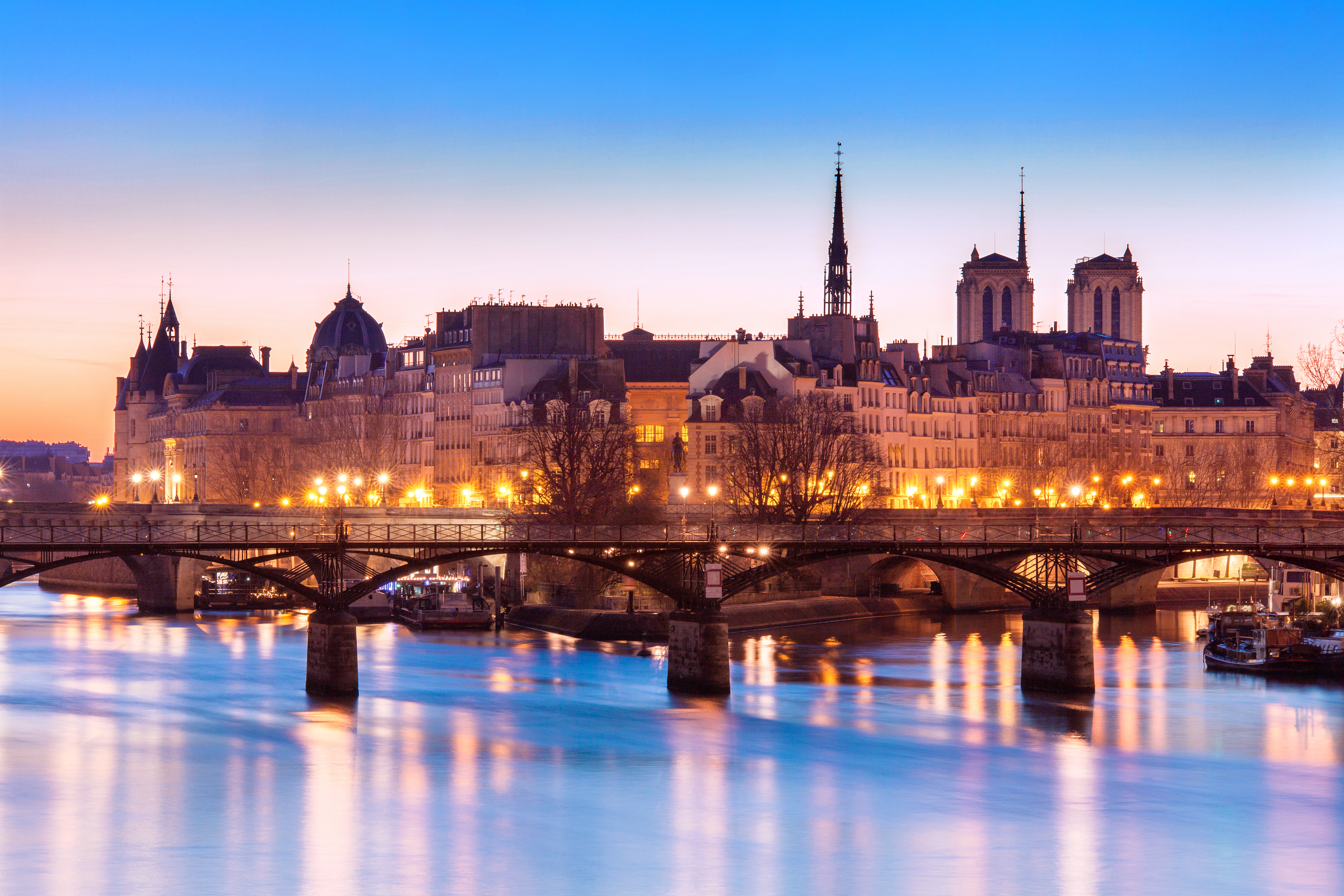 Ile de la Cite med Notre Dame Katedralen oplyst ved aftentide med Seine flodens blå reflektioner i Paris