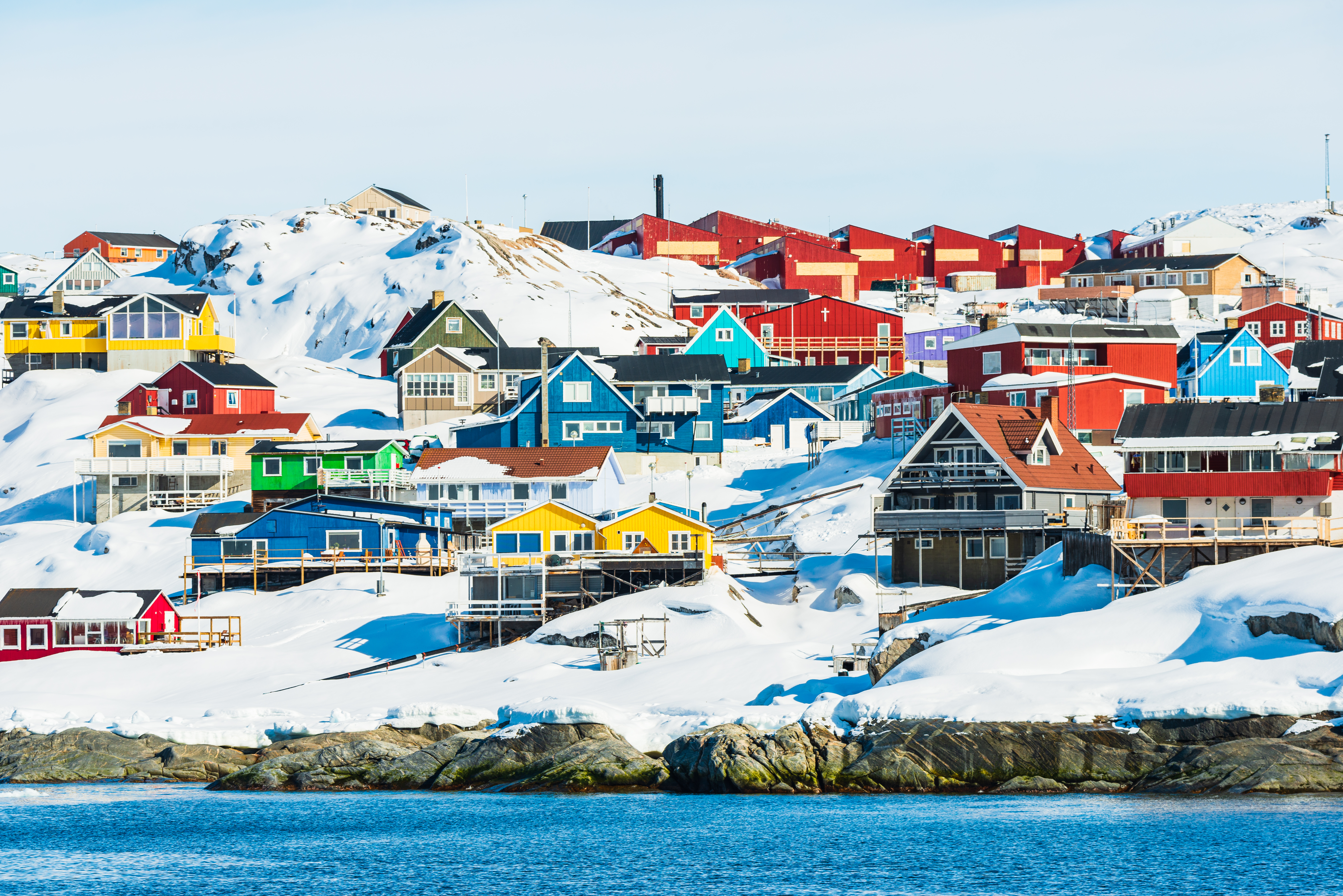 Farverige huse i det arktiske vinterlandskab i Ilulissat, Grønland, med sne og havudsigt