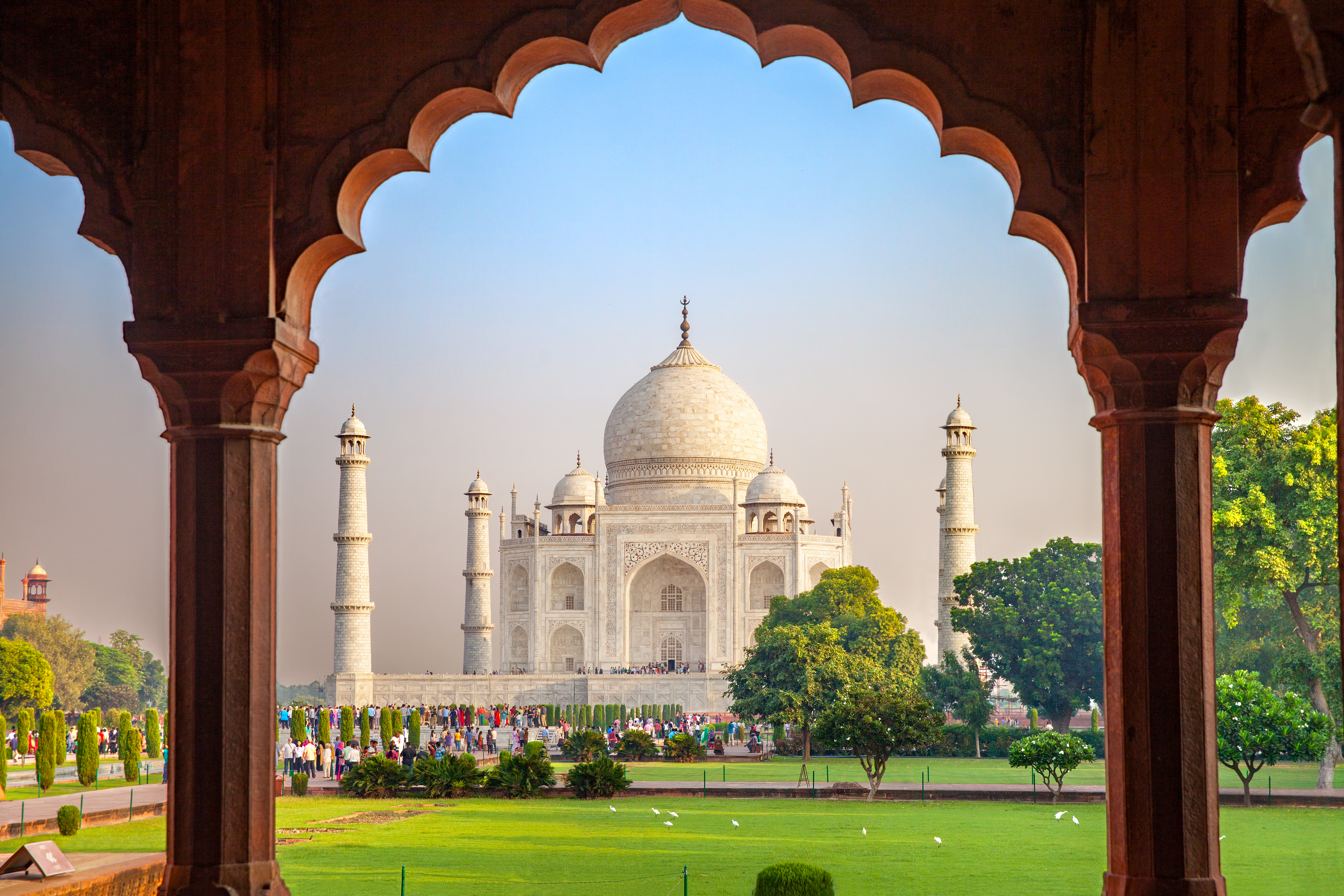 Indiens mest berømte seværdighed Taj Mahal i Agra set gennem rød sandsten portal med turister