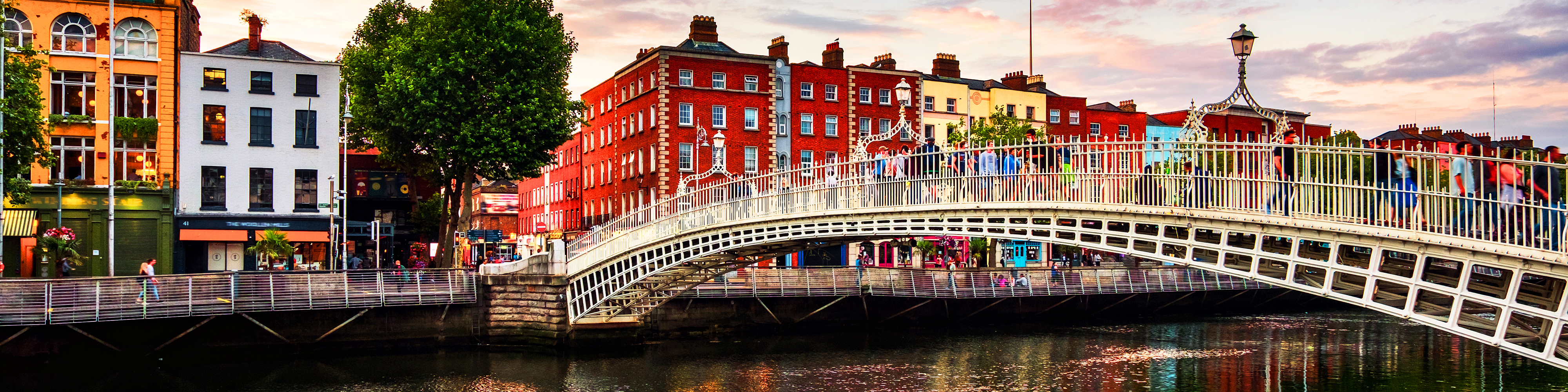 Romantisk aftenstemning ved den oplyste Ha'penny Bridge i Dublin med den blå times farver på himlen og refleksioner i vandet