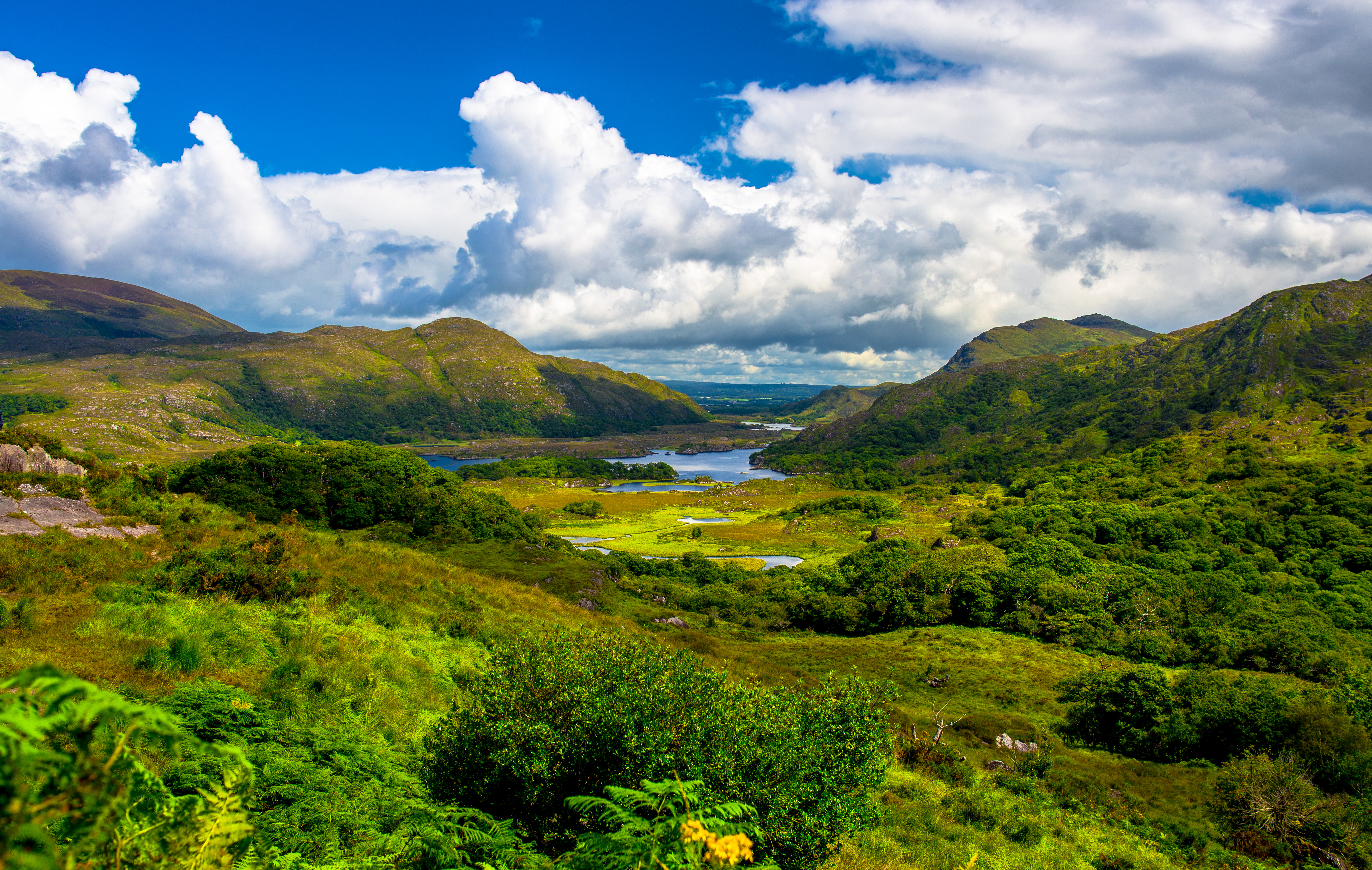 Storslået naturudsigt over Killarney National Park med grønne bjerge, blå søer og dramatisk skyfyldt himmel i County Kerry, Irland