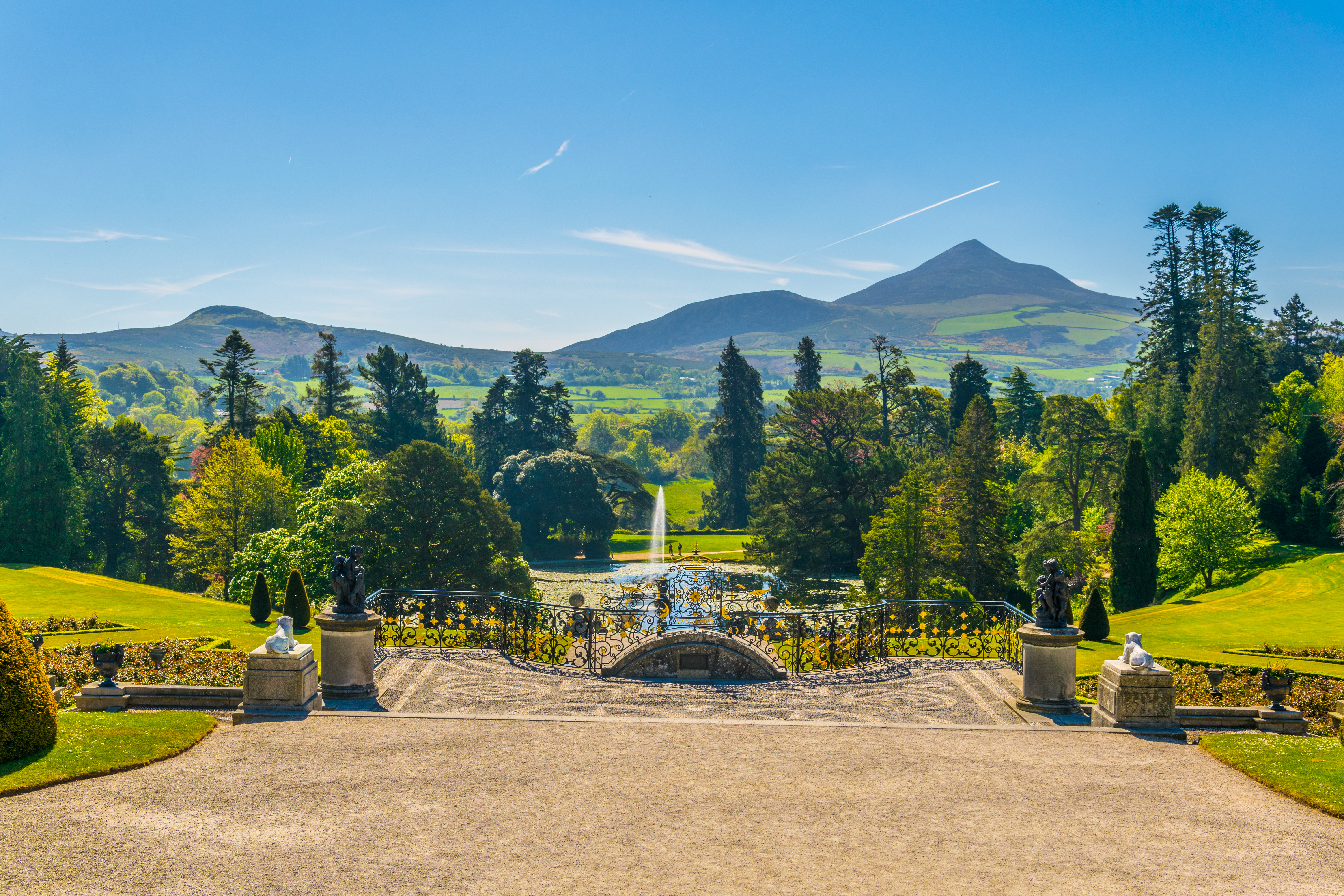 Smuk udsigt over de historiske Powerscourt-haver med dekorativt smedejernsgitter, springvand og Sugar Loaf Mountain i baggrunden, Irland