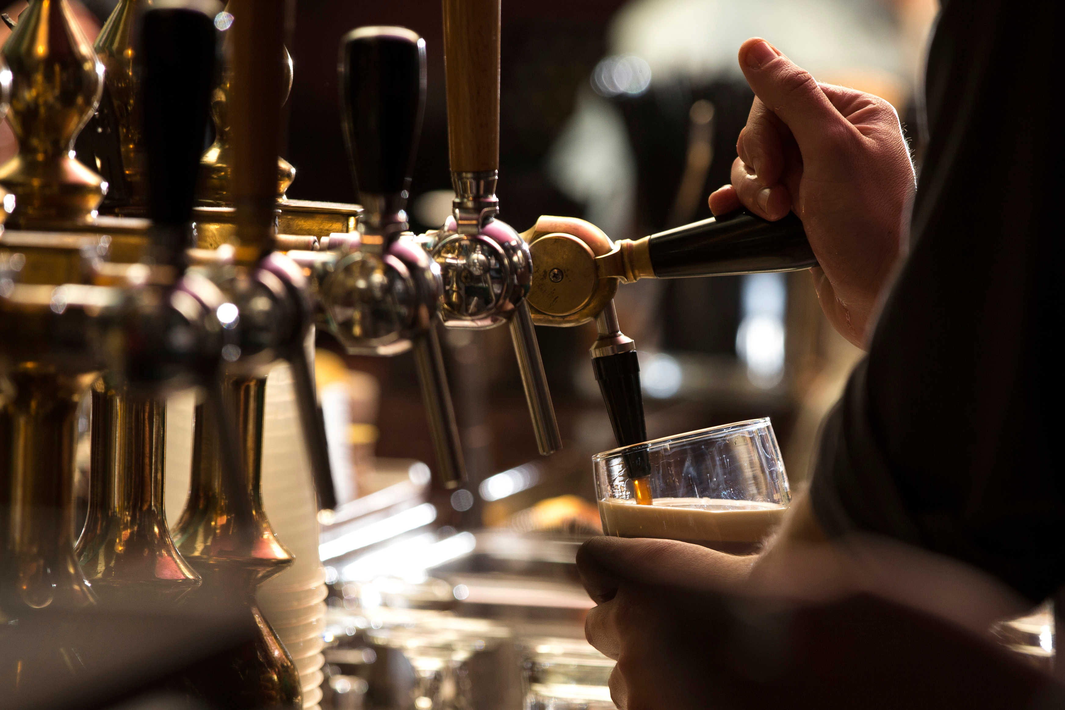 Nærbillede af en bartender der omhyggeligt skænker en mørk stout øl i en traditionel irsk pub, en kulturel smagsoplevelse