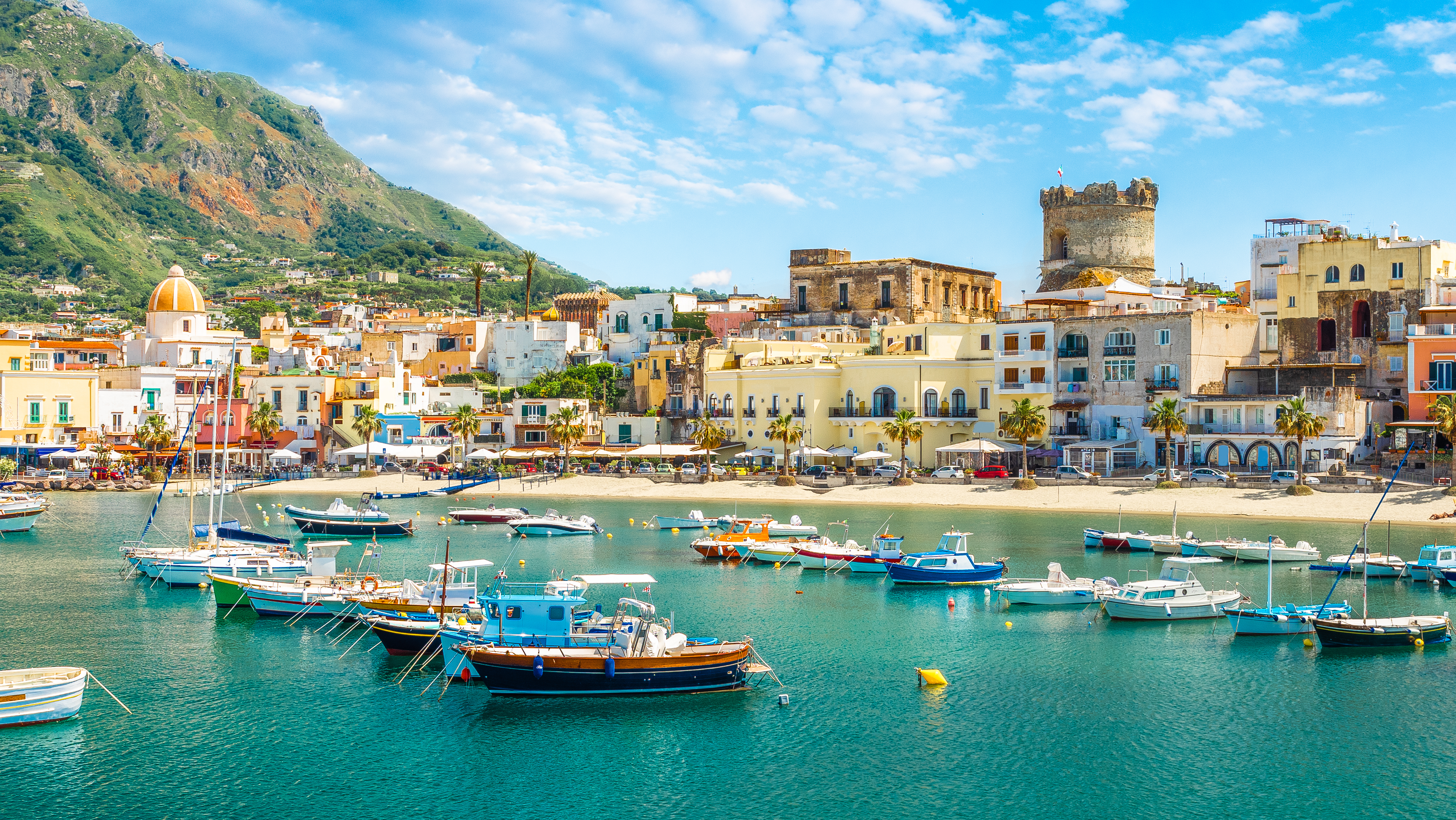 Malerisk panorama over Forio på Ischia med azurblåt vand, sandstrande og grønne bjerge, en skjult perle i Middelhavet nær Napoli