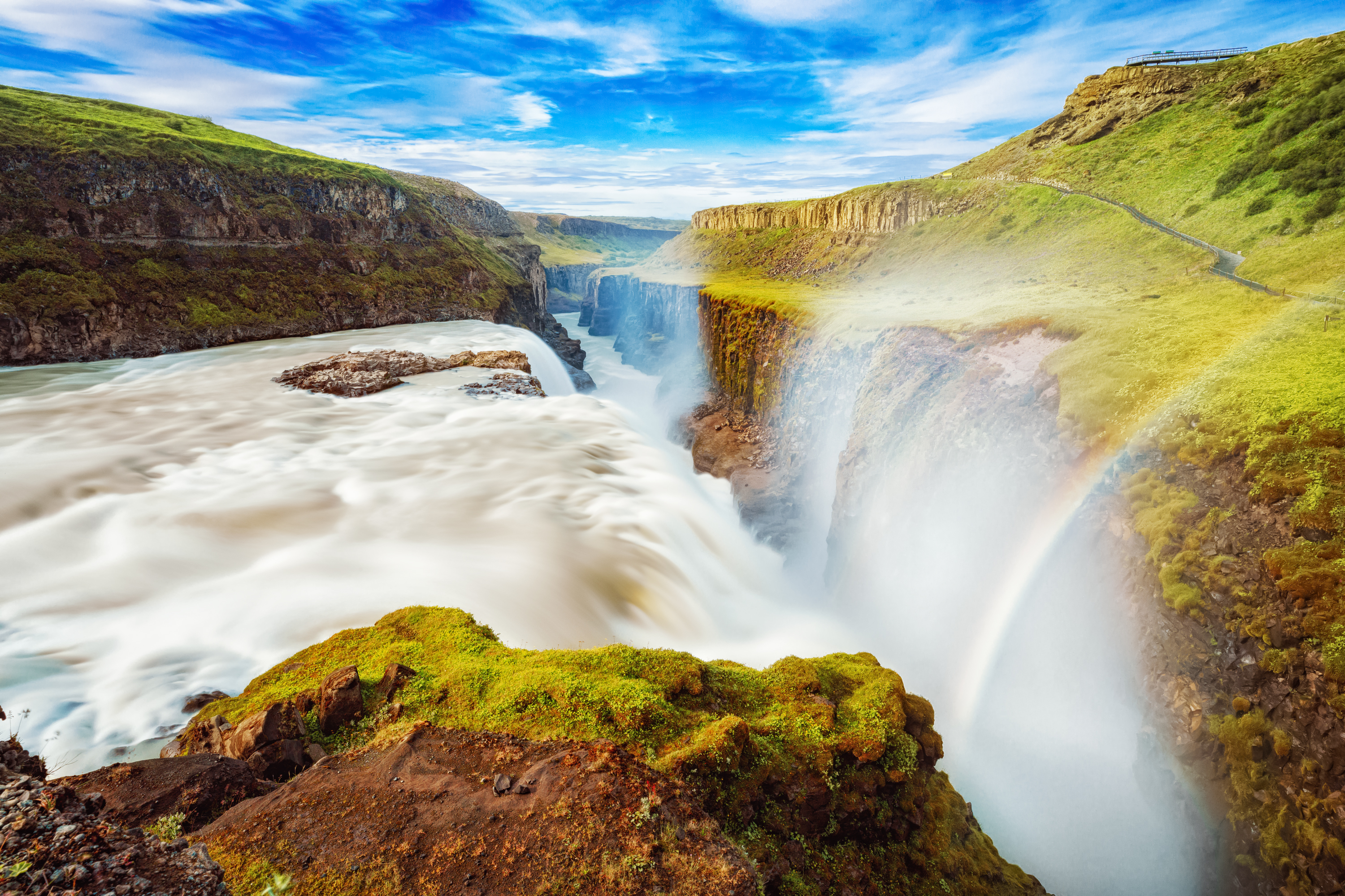 Islands berømte Gullfoss vandfald med regnbue og grøn vulkansk natur i baggrunden