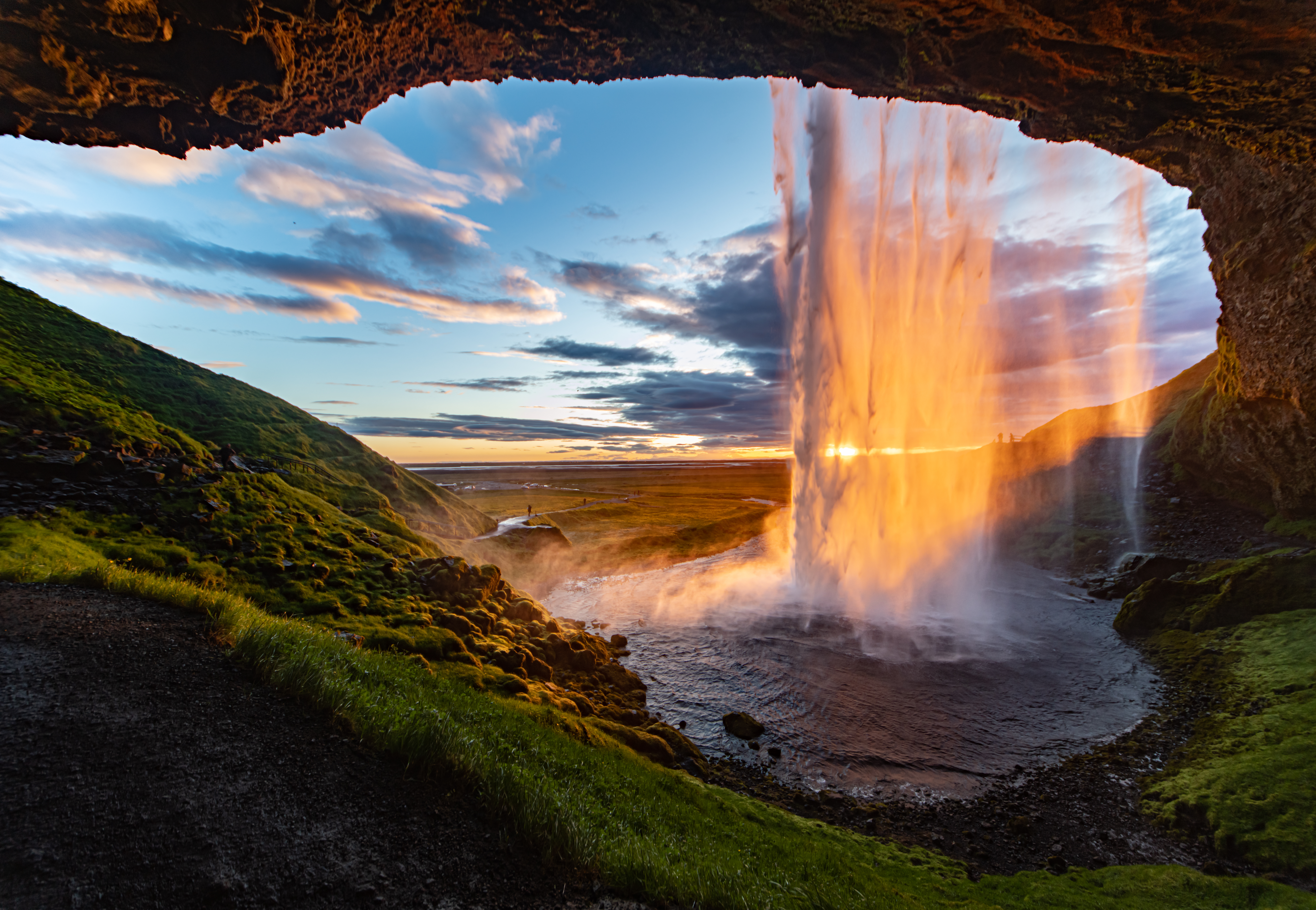 Eventyrlig udsigt bag det berømte Seljalandsfoss vandfald på Island, oplyst af midnatssolen i en magisk sommer nat