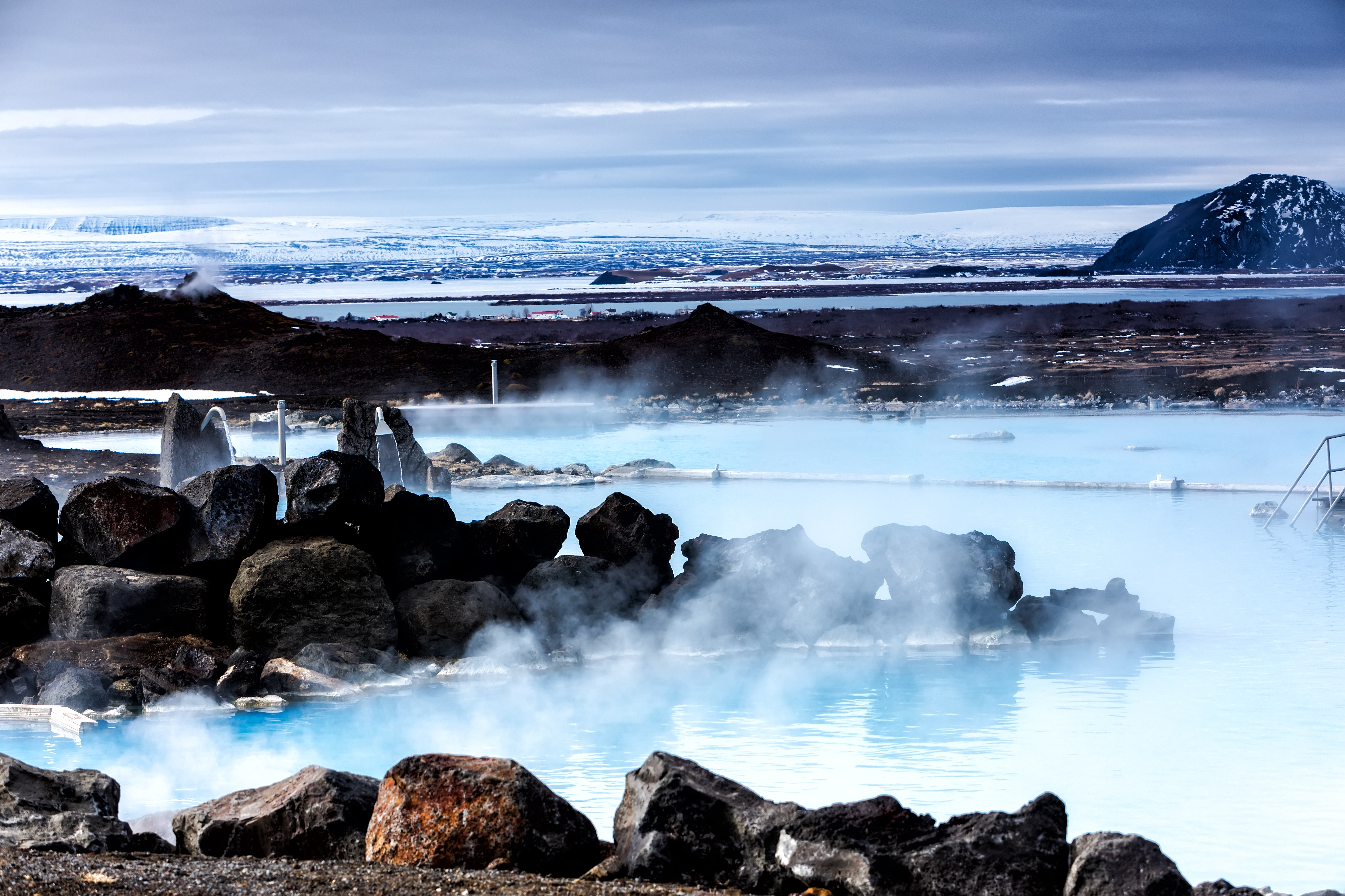 Vulkanske varme kilder spa med blåt geotermisk vand omgivet af lavasten på Island
