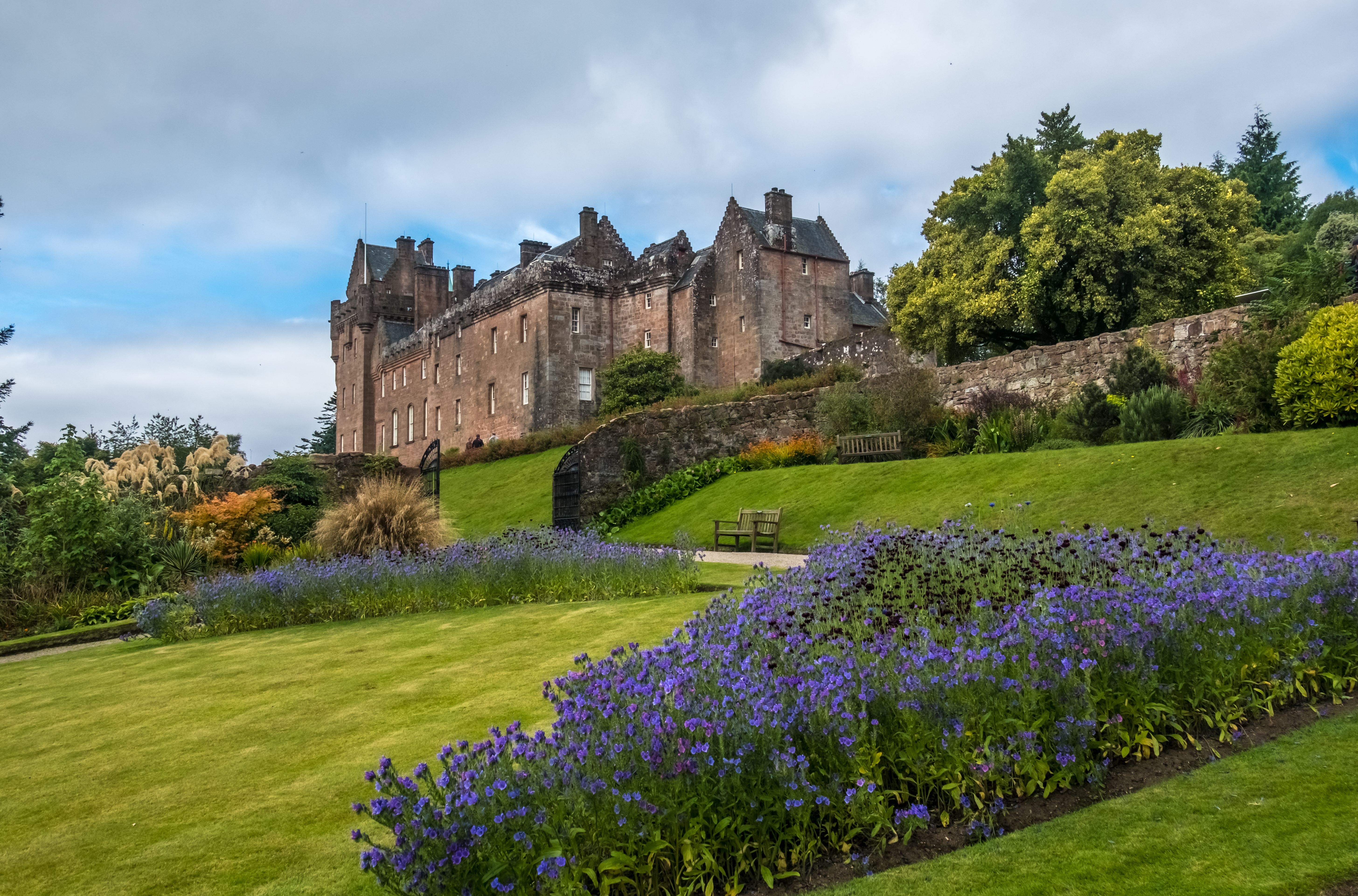 Malerisk udsigt til Brodick Castle på Isle of Arran i Skotland med blomstrende haver og dramatisk himmel