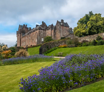 Malerisk udsigt til Brodick Castle på Isle of Arran i Skotland med blomstrende haver og dramatisk himmel