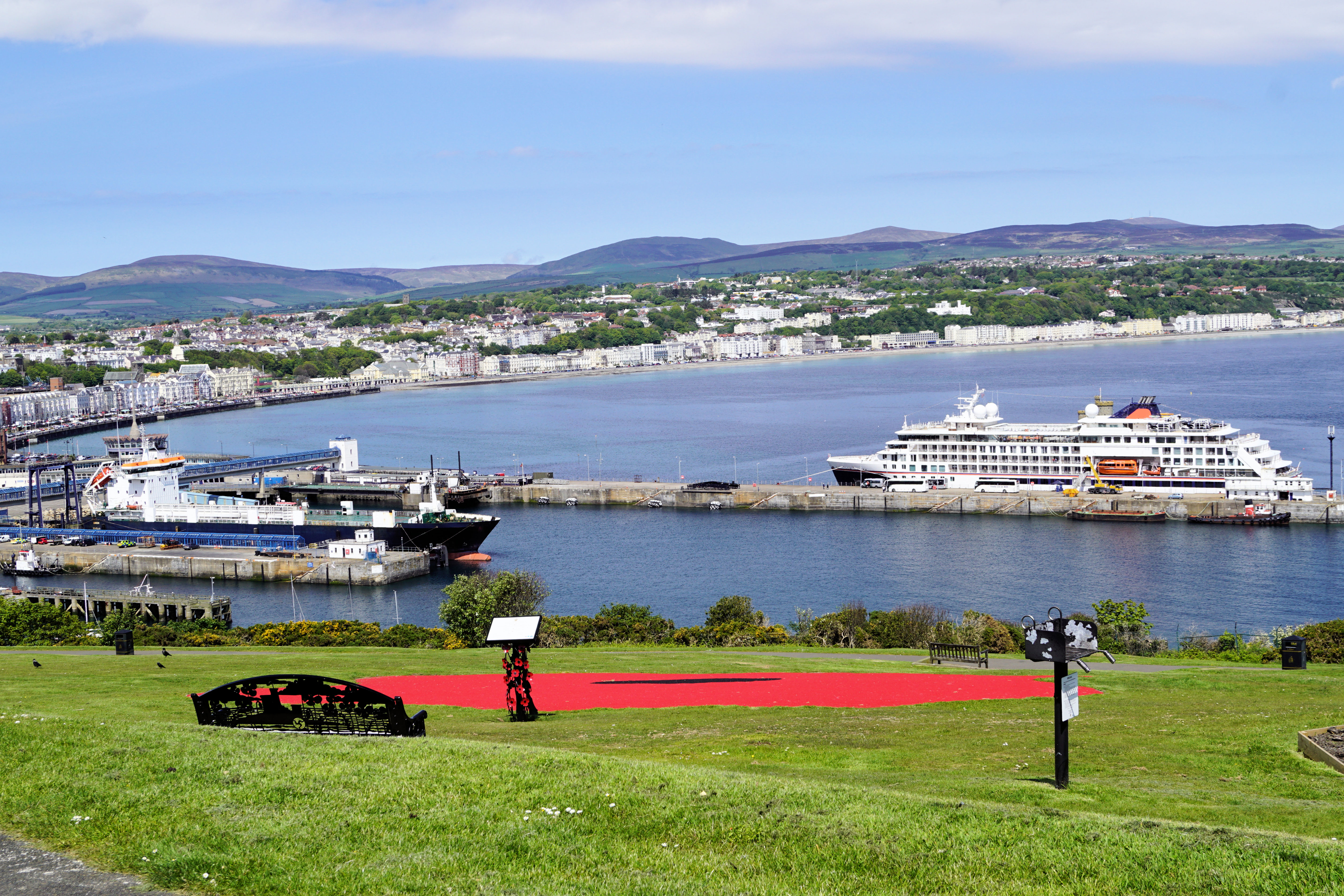 Smuk udsigt over Douglas havn med krydstogtskib og grønne landskaber på Isle of Man