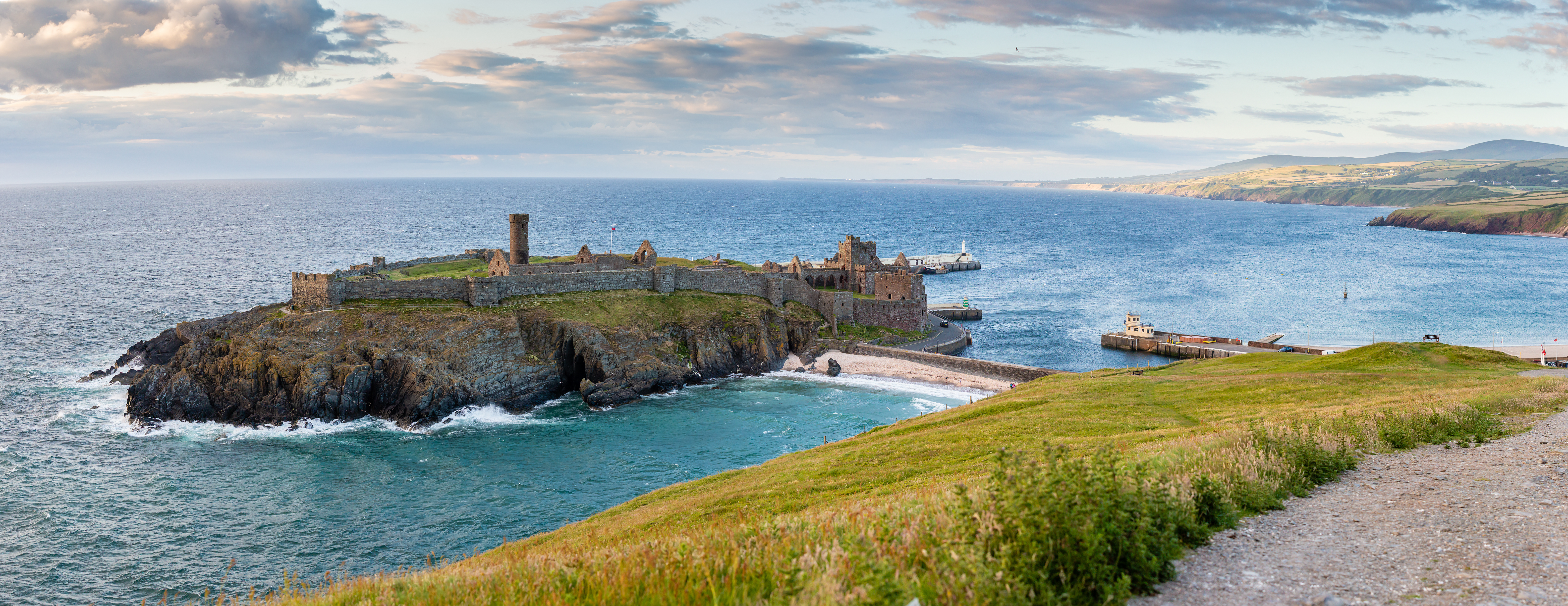 Imponerende ruiner af Peel Castle på klippeø med middelalderlig havn og skønne turkise havfarver på Isle of Man