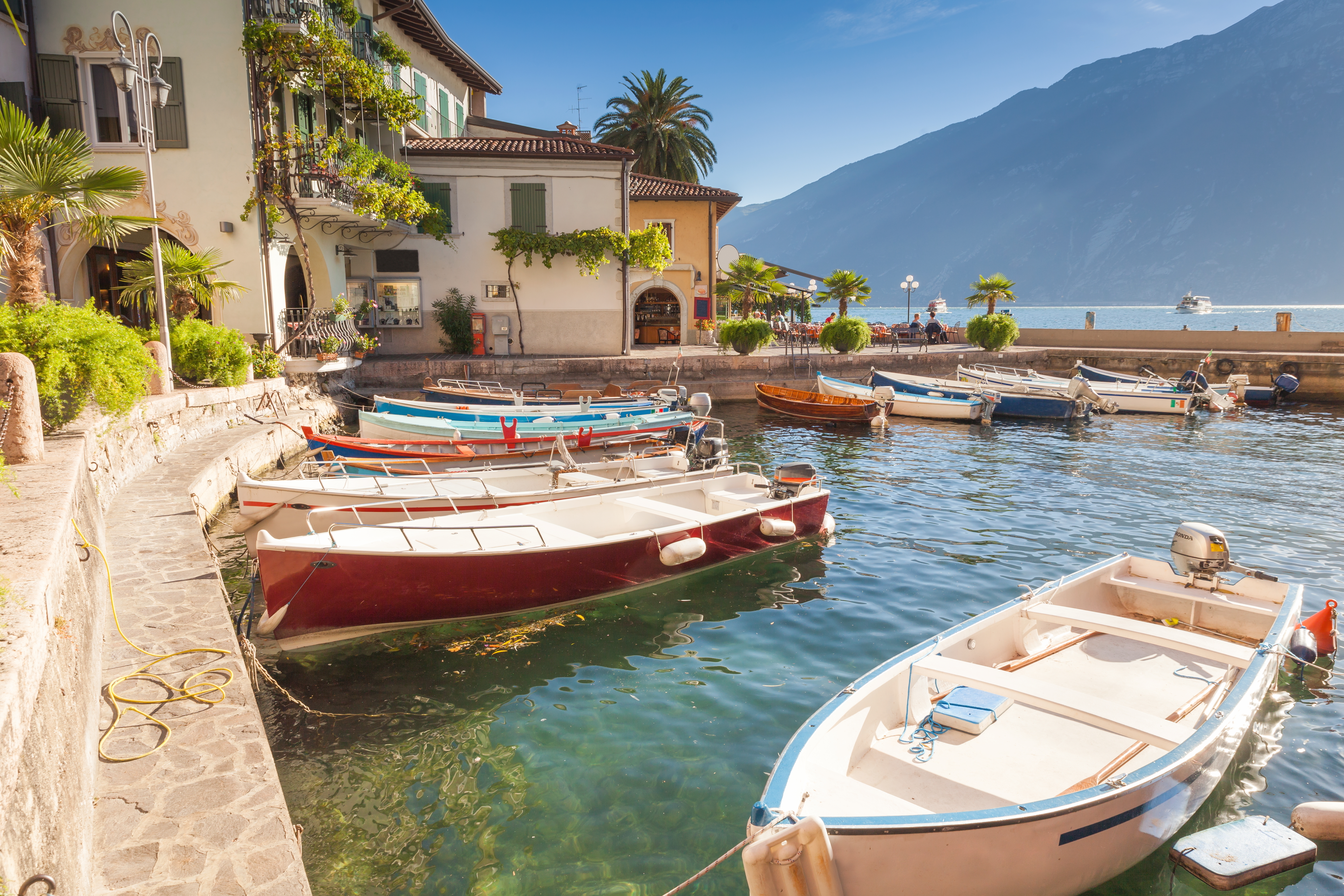 Smuk italiensk fiskerhavn ved Gardasøen med farverige både og traditionel middelhavs arkitektur